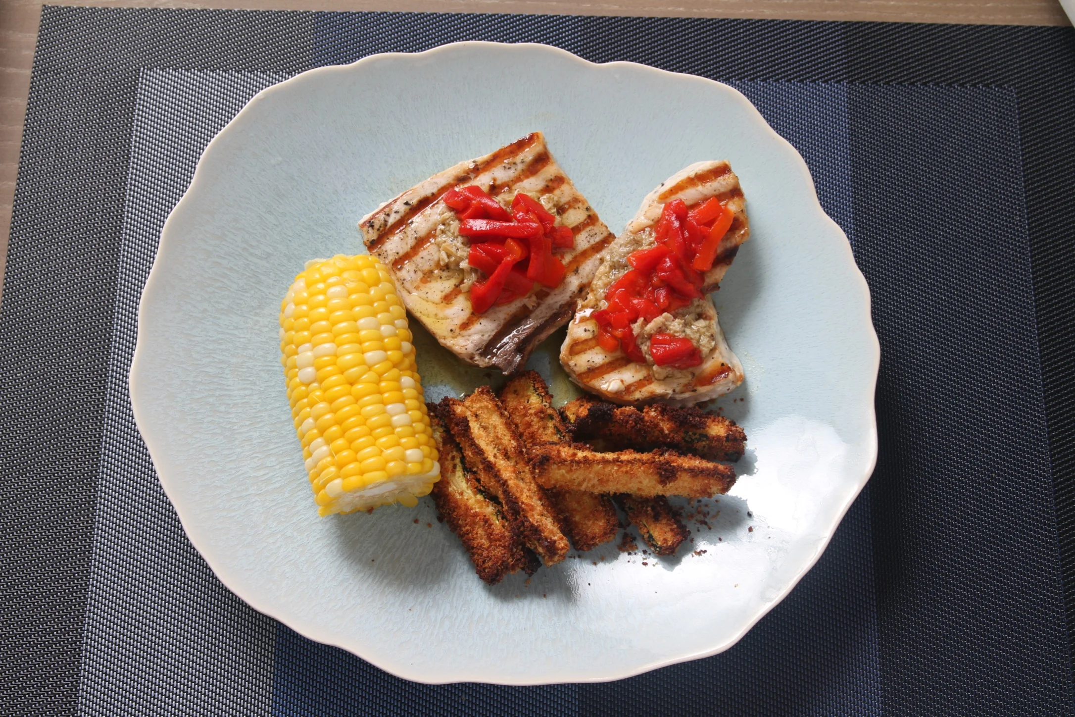 Pan-grilled swordfish with baked zucchini sticks and corn-on-the-cob.