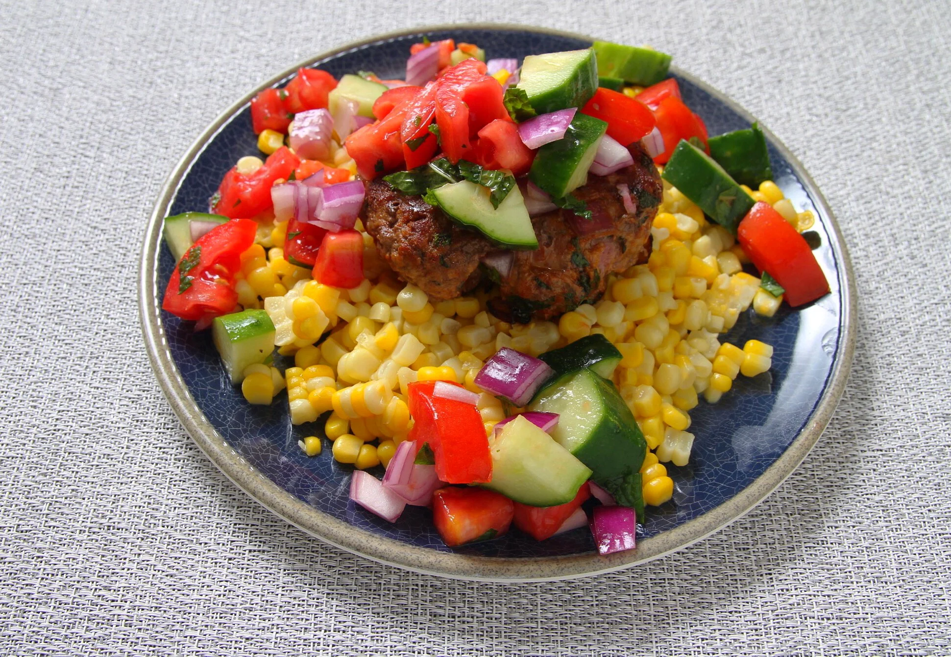 Lamb burger with Greek salad and sweet corn. 