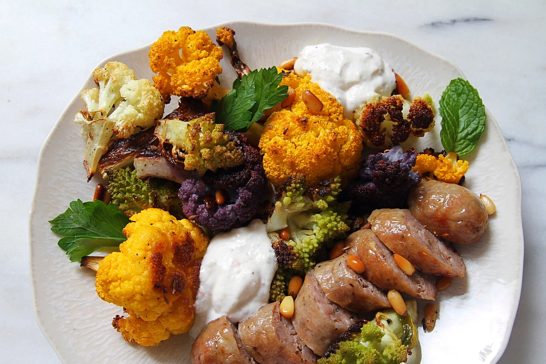 Roasted sausages and cauliflower with cumin seeds and pine nuts.