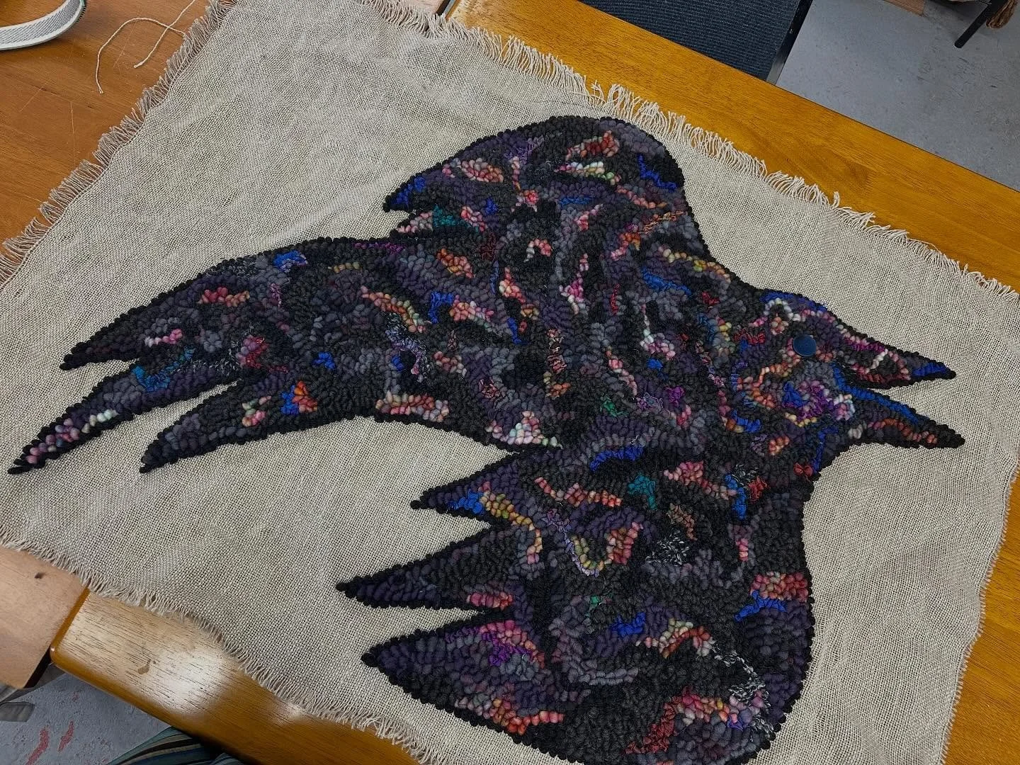 Gluing the edges of my crow since I finally finished hooking it last night. I&rsquo;m considering an iridescent button for its eyeball. What do we think? #rughooking #hookedrug #rughookersofinstagram #rugmaking #fiberart #textileart #fiberartist #tex