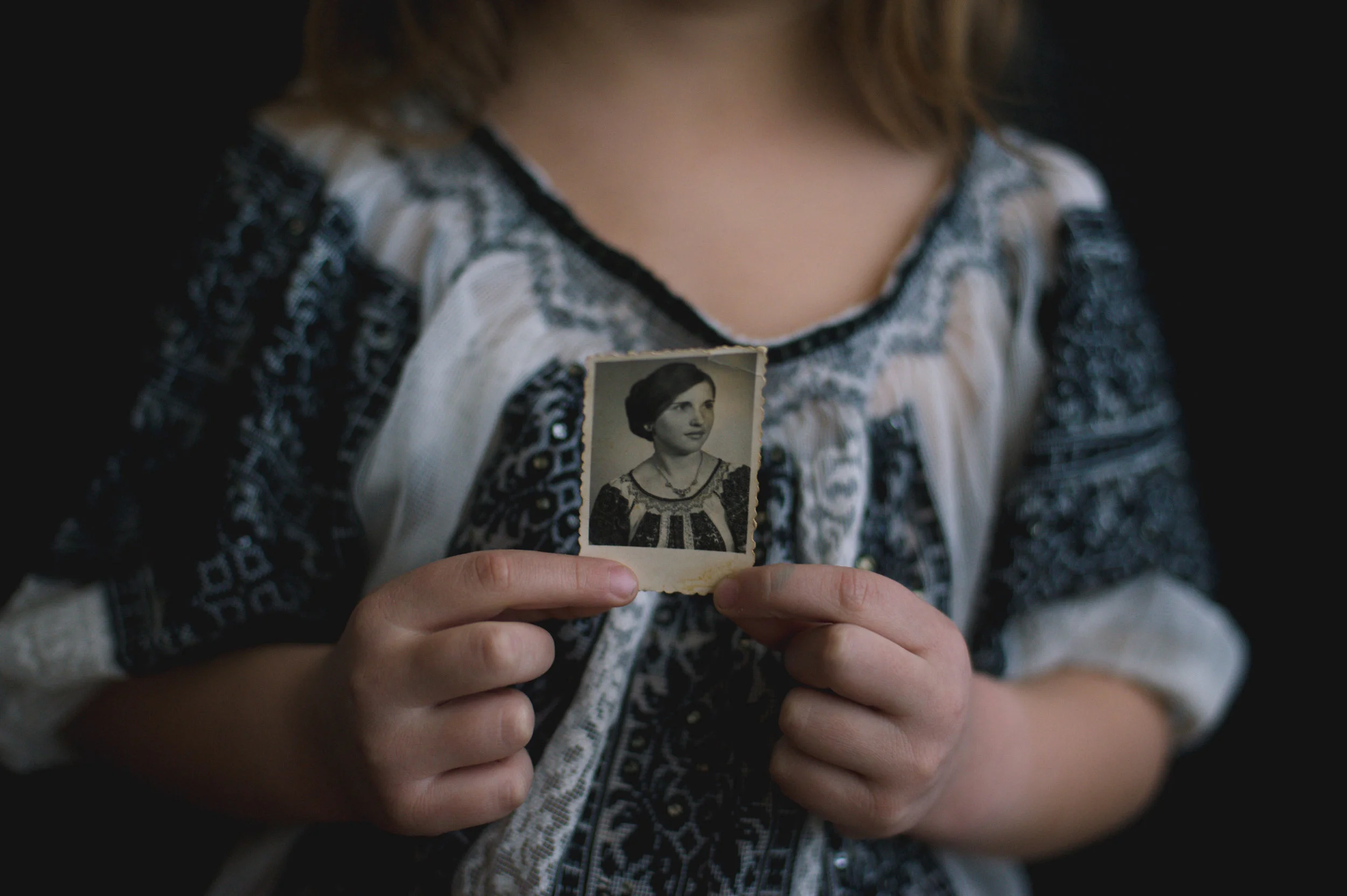 Adina's daughter, Ilinca (5), wears the same embroidered shirt as her grandmother (Adina's mother) in the photo she holds.