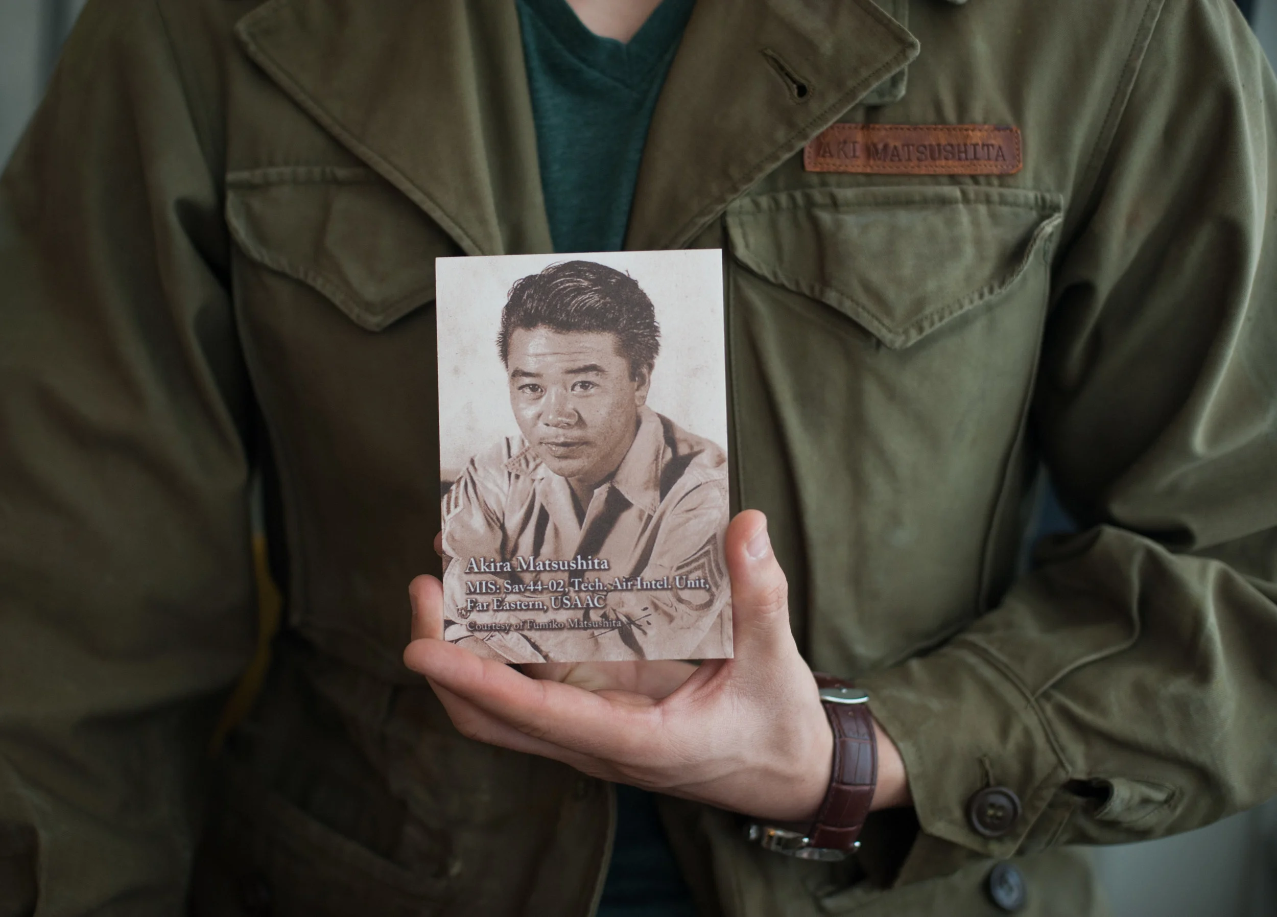 Josh, wearing his grandfather's US Army jacket and holding his grandfather's US Army photo. 