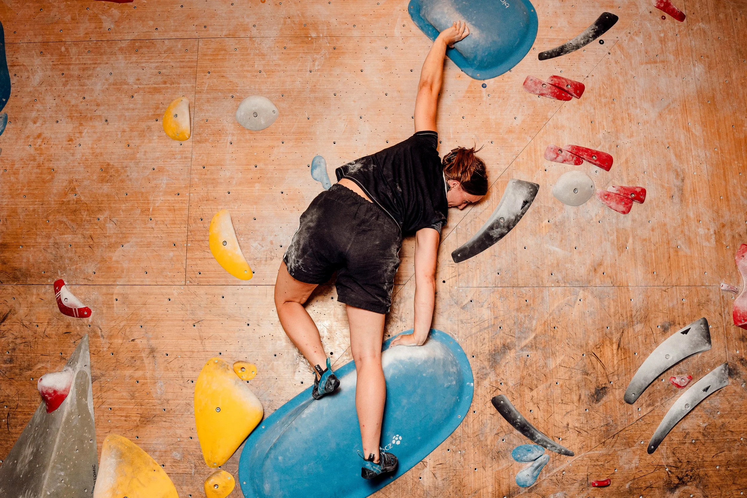 woman climbing blue boulder
