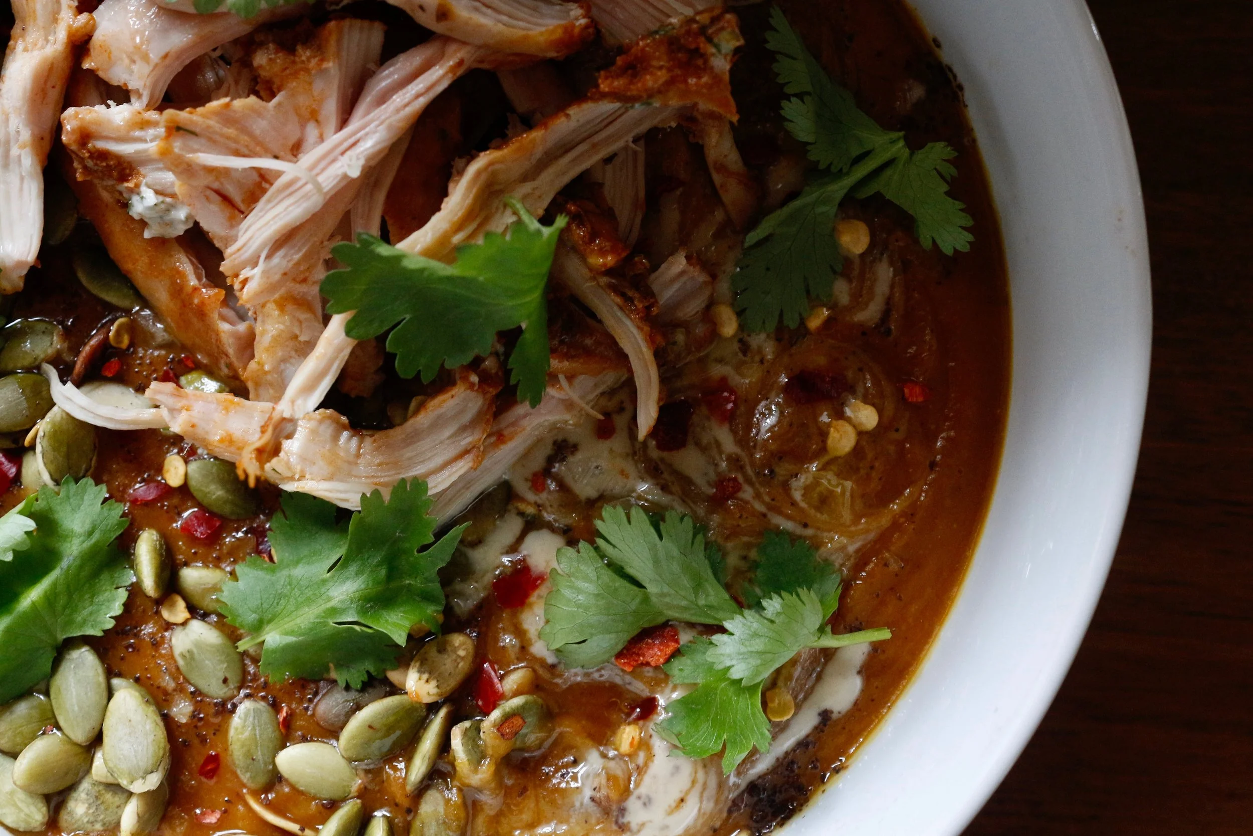 This soup gets its velvety texture from sweet potato, butternut squash, cauliflower, and red lentils. The starch helps to achieve a creamy purée without the need to add any actual cream. Red chiles, red miso, turmeric, mustard powder, and a splash of apple cider vinegar add punchy flavor and nutrition. Topped with a swirl of yogurt and tahini, pepitas, cilantro, sumac, and some shredded harissa roasted chicken. 