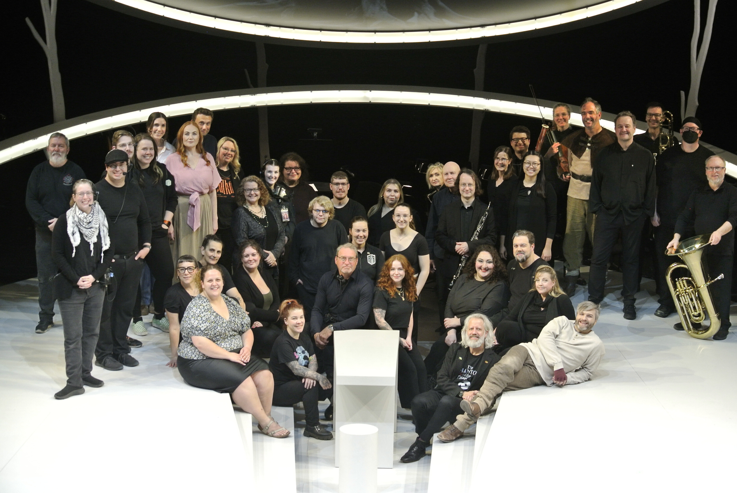 Full cast, crew, and orchestra members of Die Walküre gathered onstage in black attire for a group photo, smiling toward the camera.