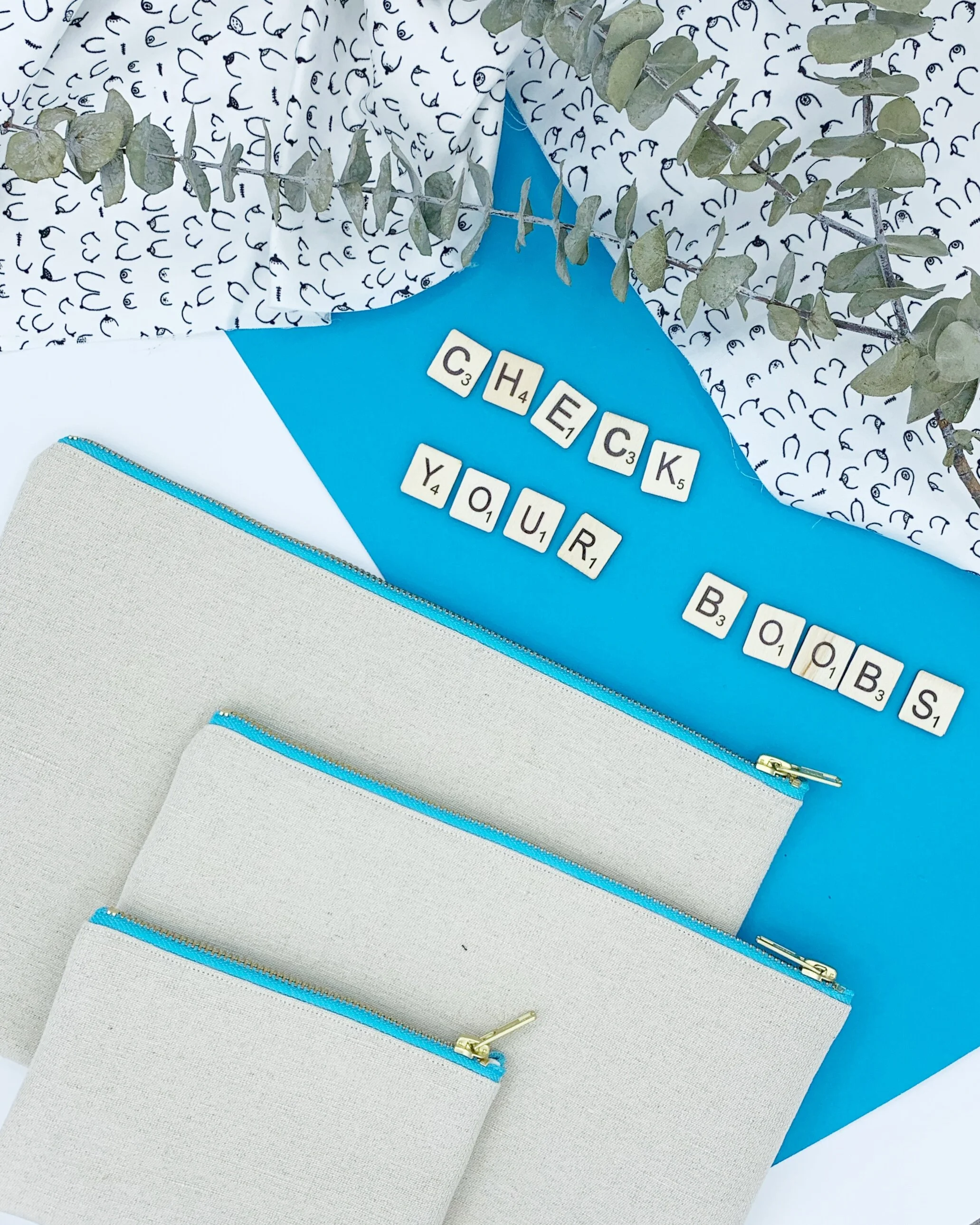 Flat lay of the B Collection clutch bags and purse with scrabble pieces spelling out check your boobs