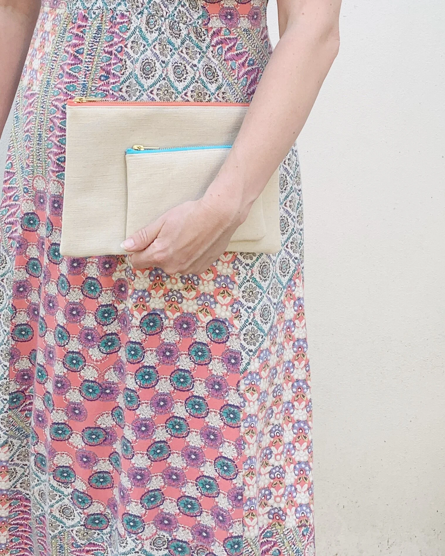 Person wearing pink purple maxi dress holding V Collection clutch coral zip B Collection purse teal zip