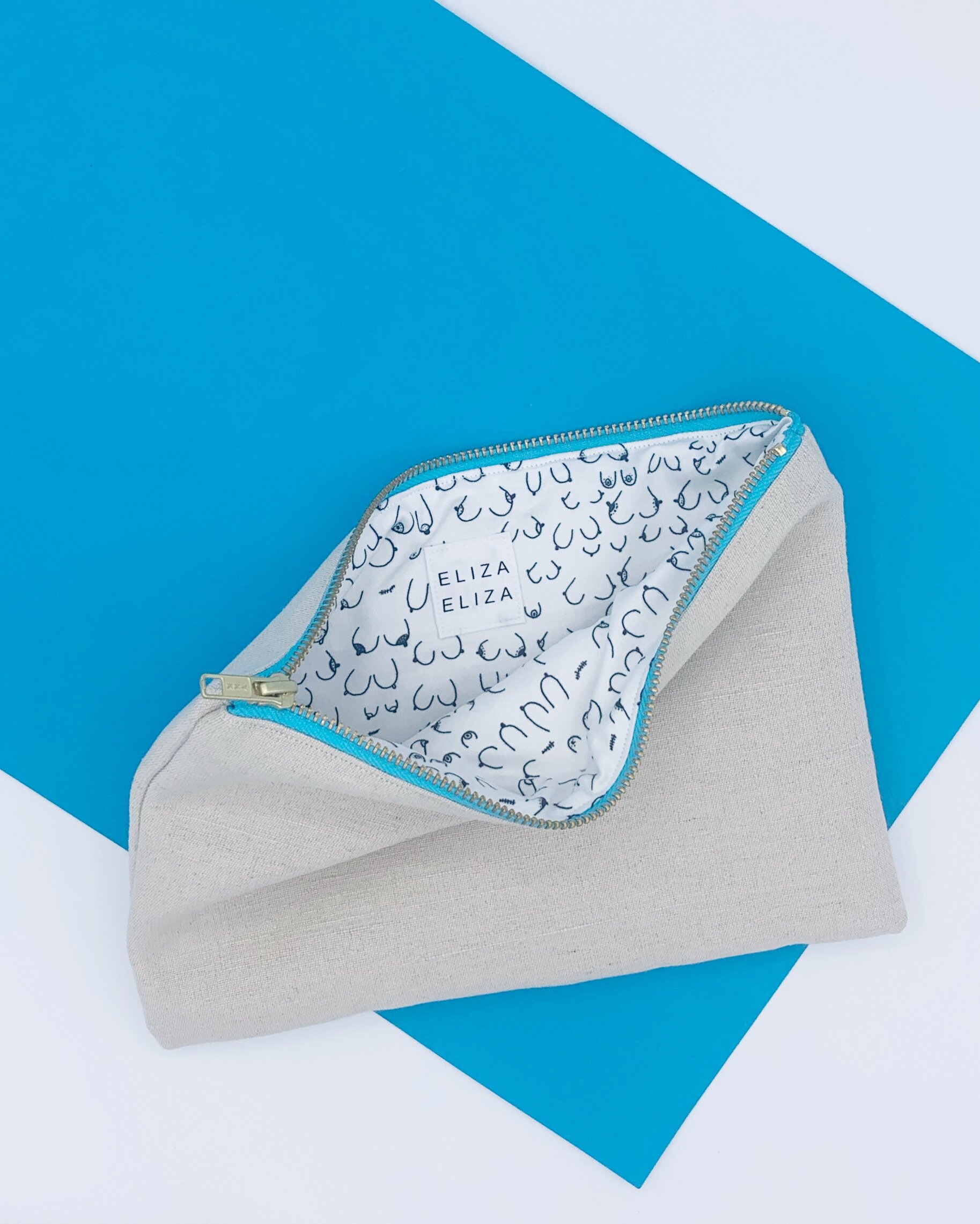 flat lay of B Collection clutch bag on blue and white background showing lining aiming to raise awareness around breast cancer