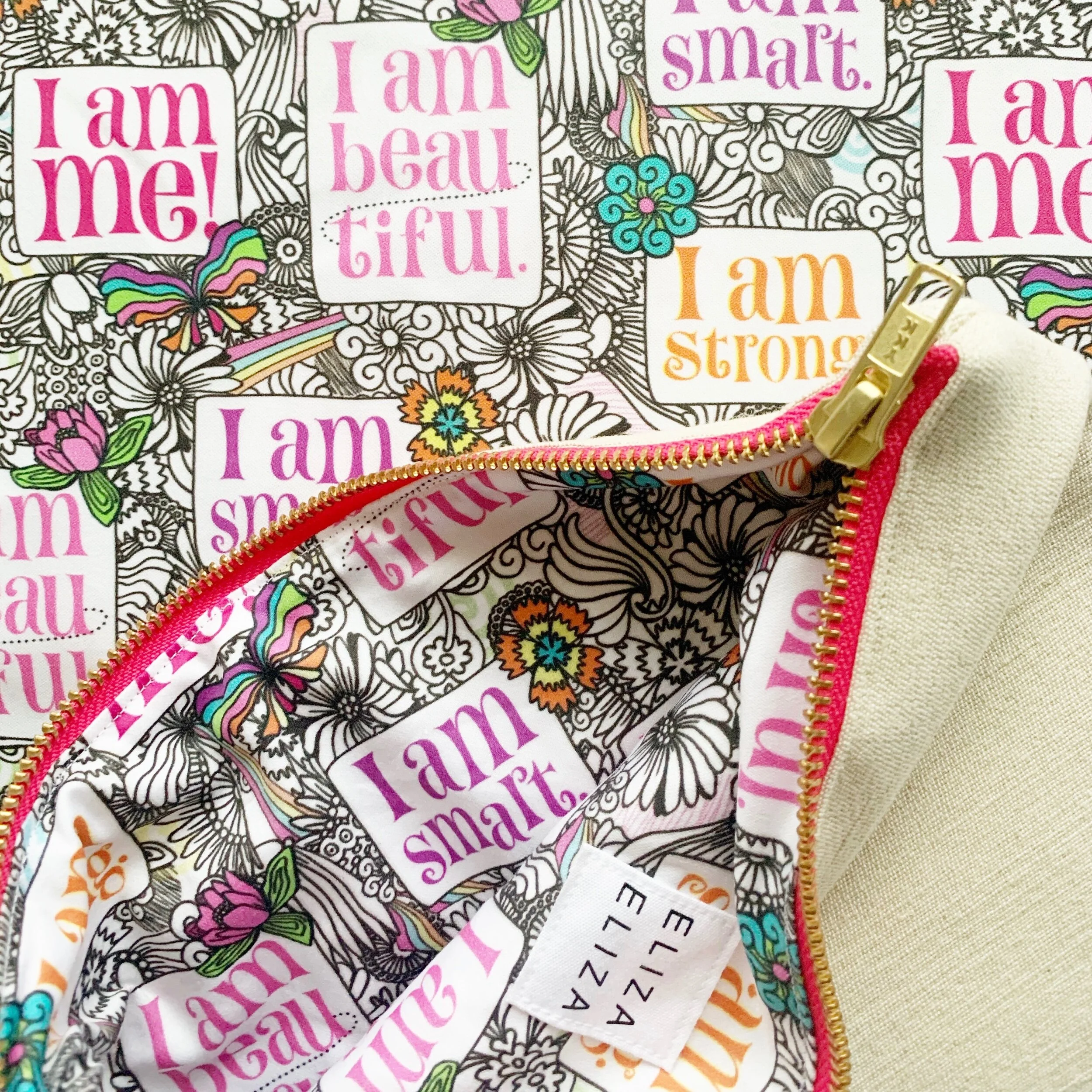Open I am Me Large clutch bag peeking open lays on coordinating fabric pattern