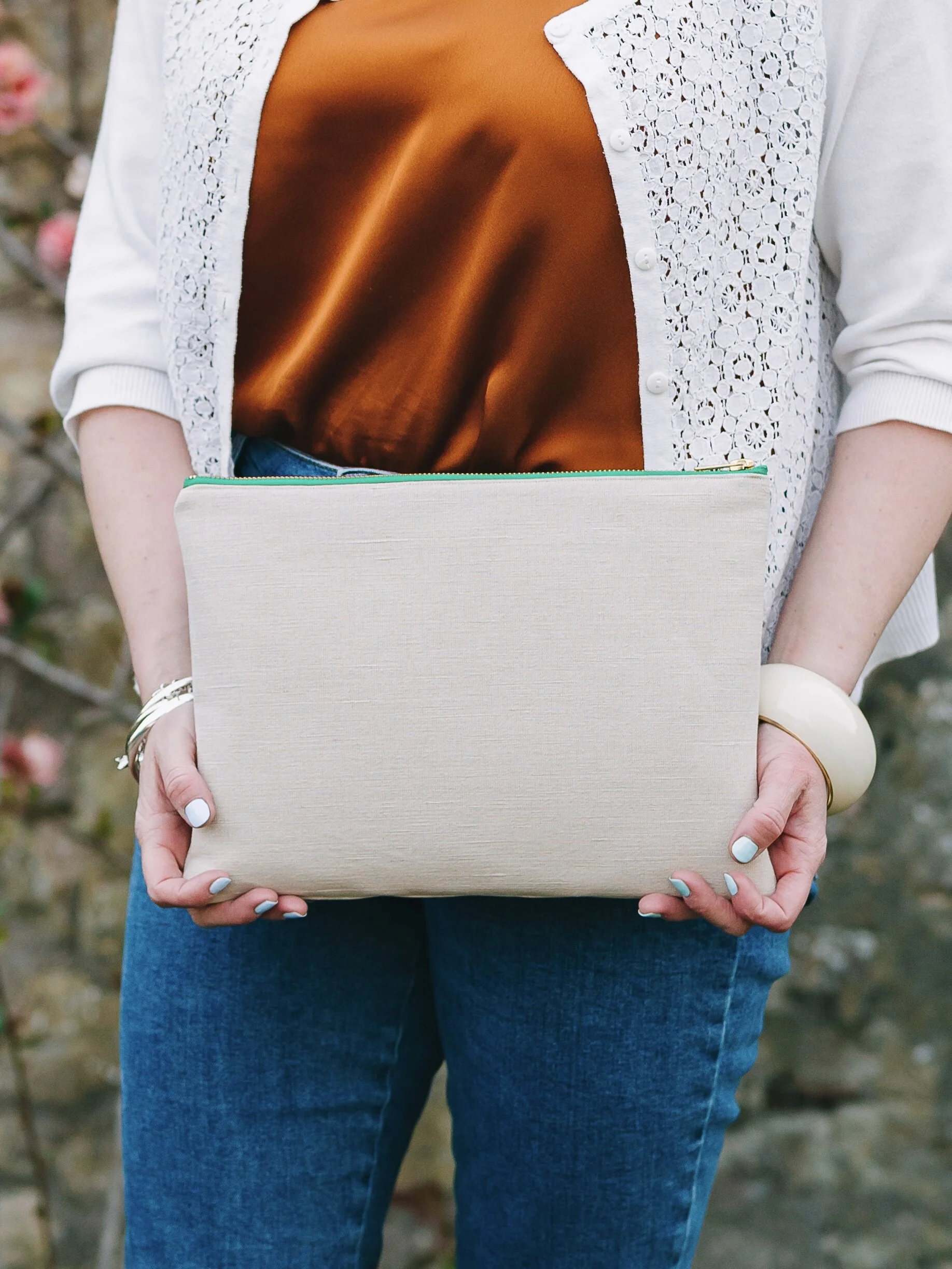 Woman holds large cream hemp clutch bag with both hands