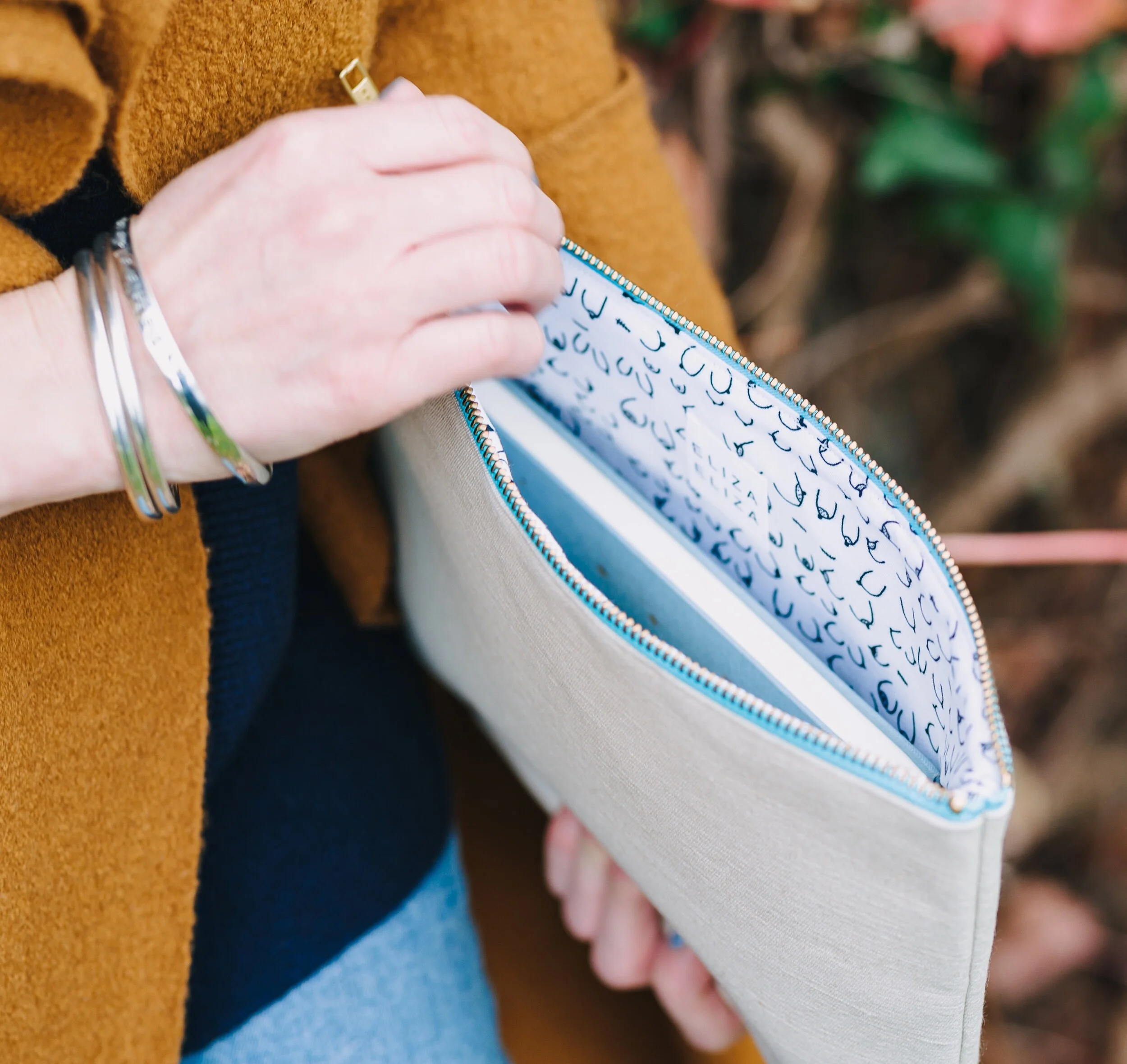 Woman holding B Collection large clutch open with blue notebook inside