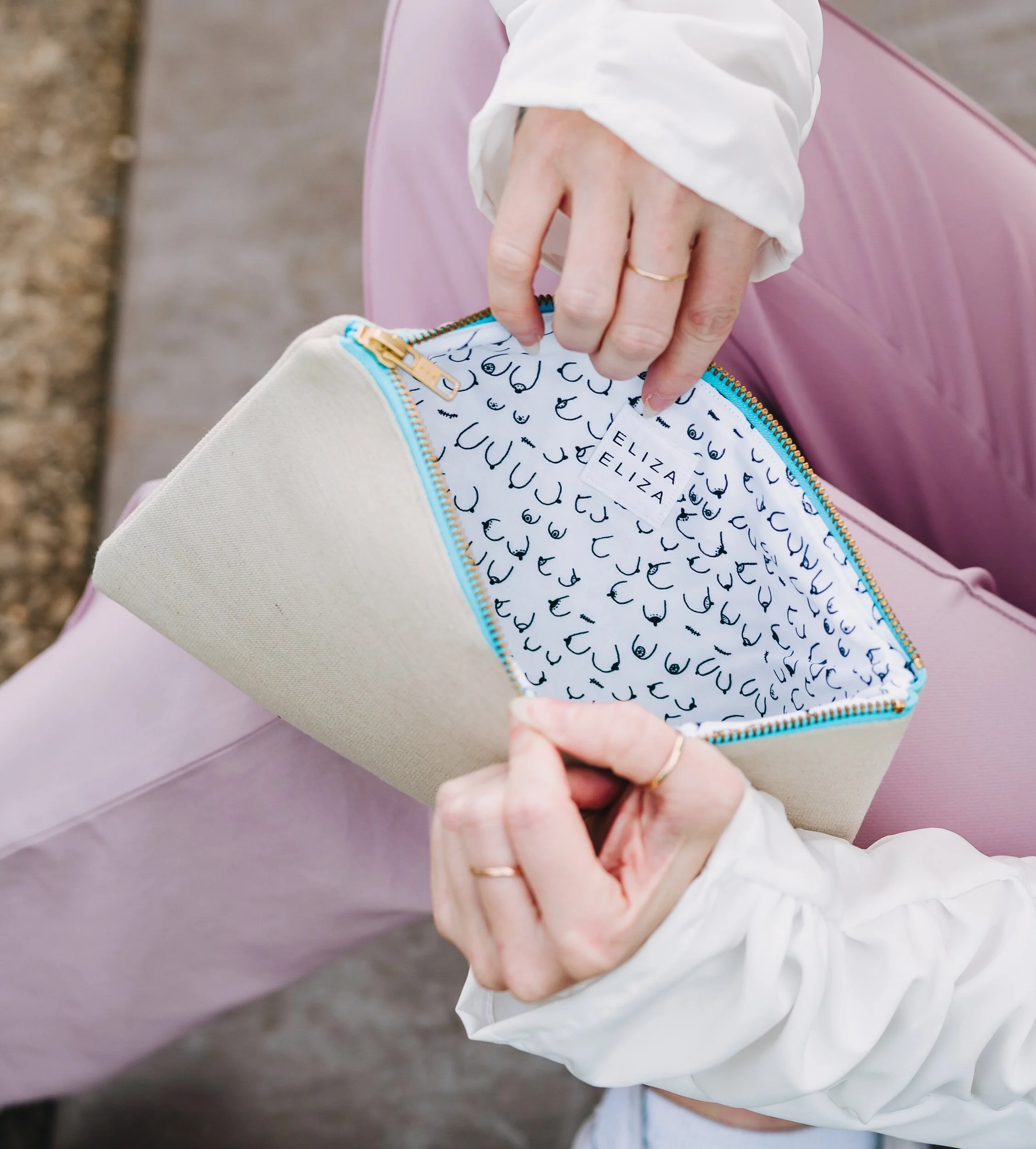 Person wearing light pink trousers and white shirt holding a B Collection clutch bag open Carry Your Cause Starting Conversations