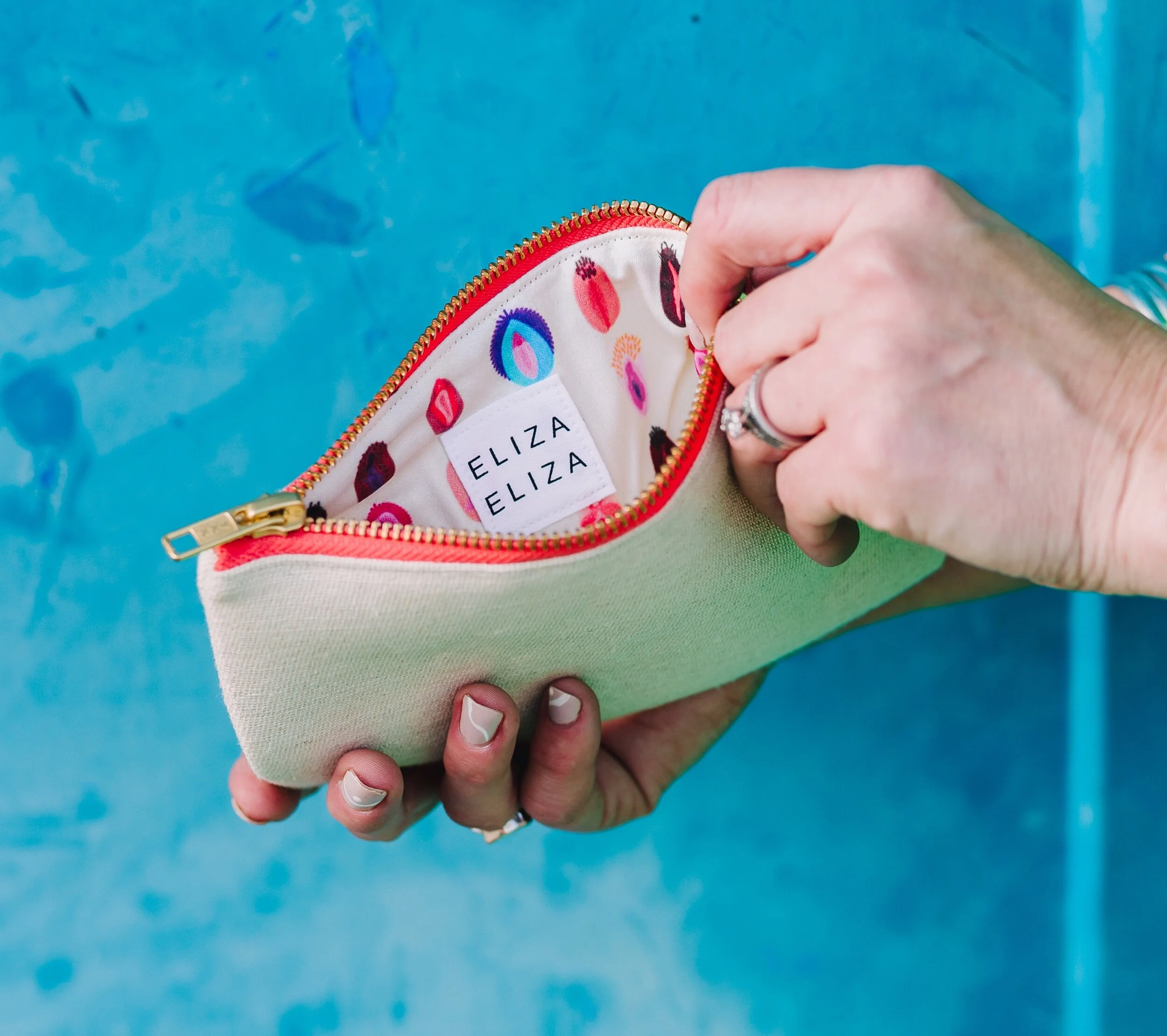 Close up person holding open V Collection showing lining with blue wall background Carry your Cause