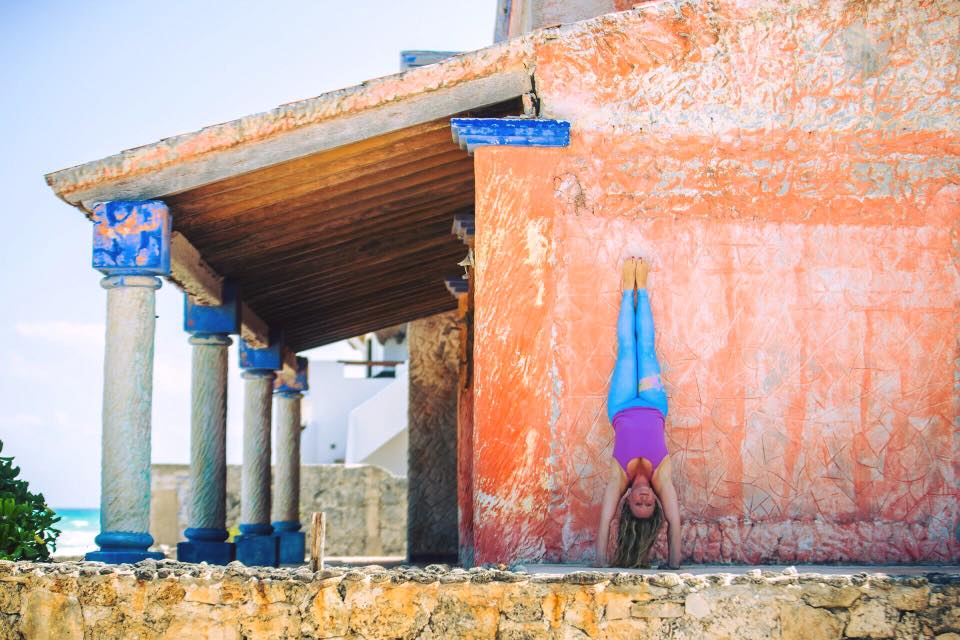 Hollow back handstand against orange wall in Tulum, in blue pants.jpg