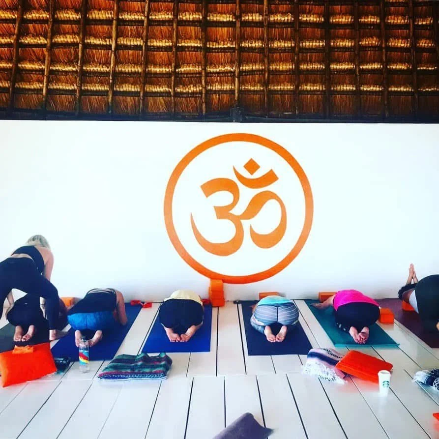 Mary giving a hands on adjustment in childs pose in tulum class .jpeg