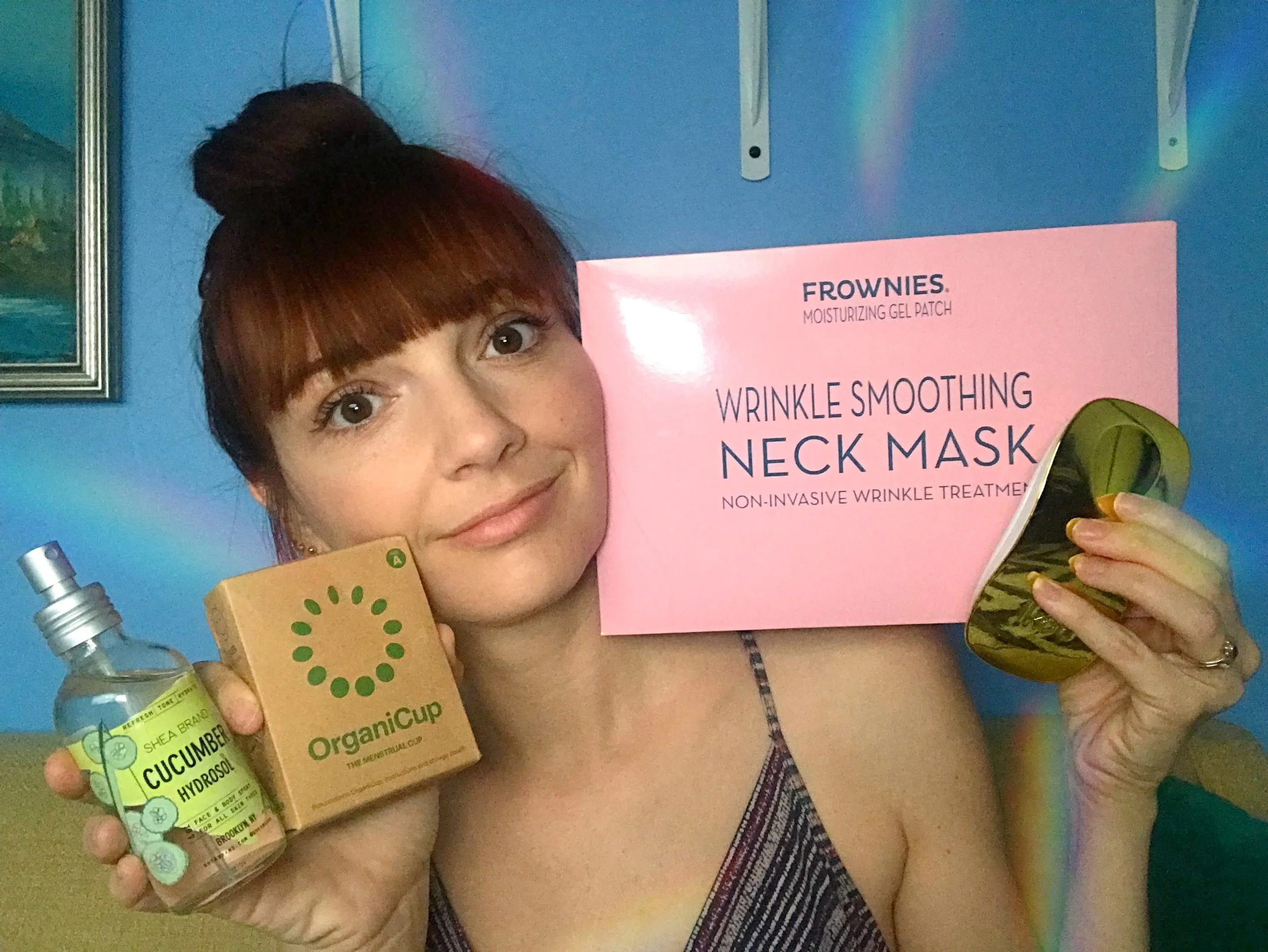 Jackie Johnson with her favorite products of the week of August 27: Frownies Neck Mask, OrganiCup, Shea Brand Cucumber Hydrosol, and Ikoo hairbrush.
