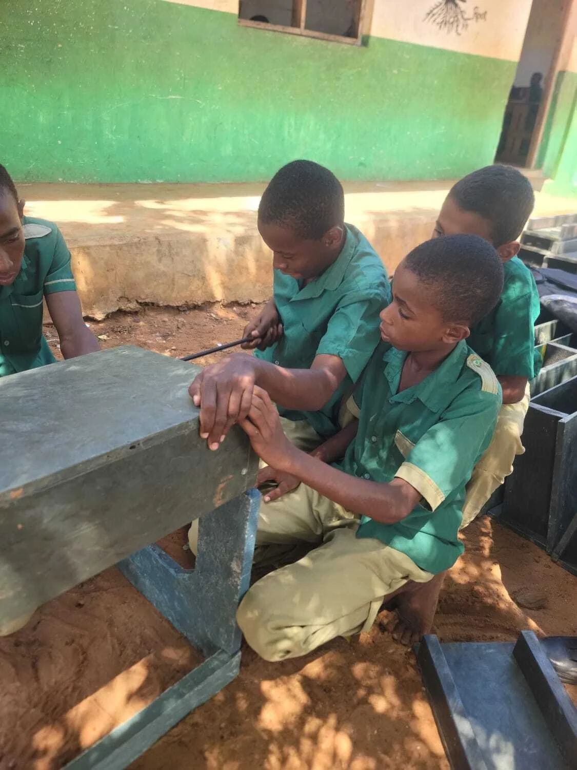 4 students working together to construct a recycled plastic school desk