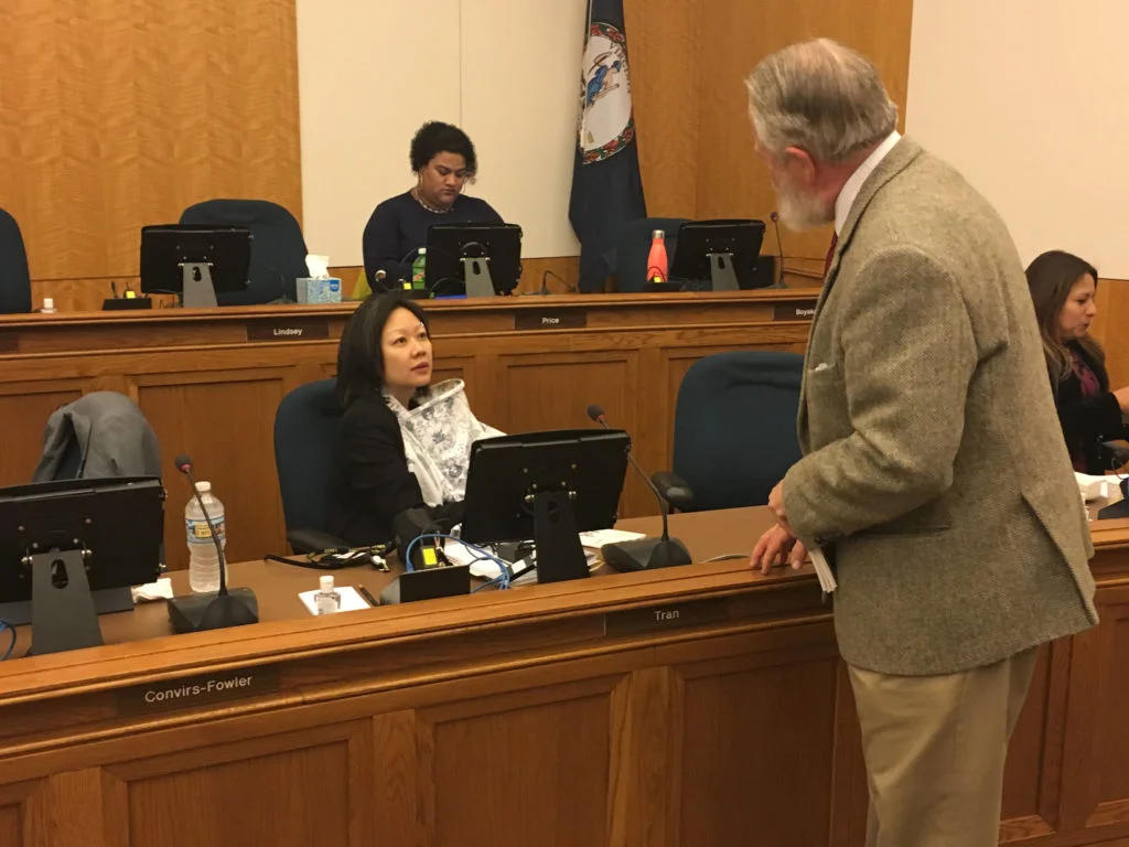 Tran talks with a lobbyist while nursing during a hearing. Tyone Turner / WAM