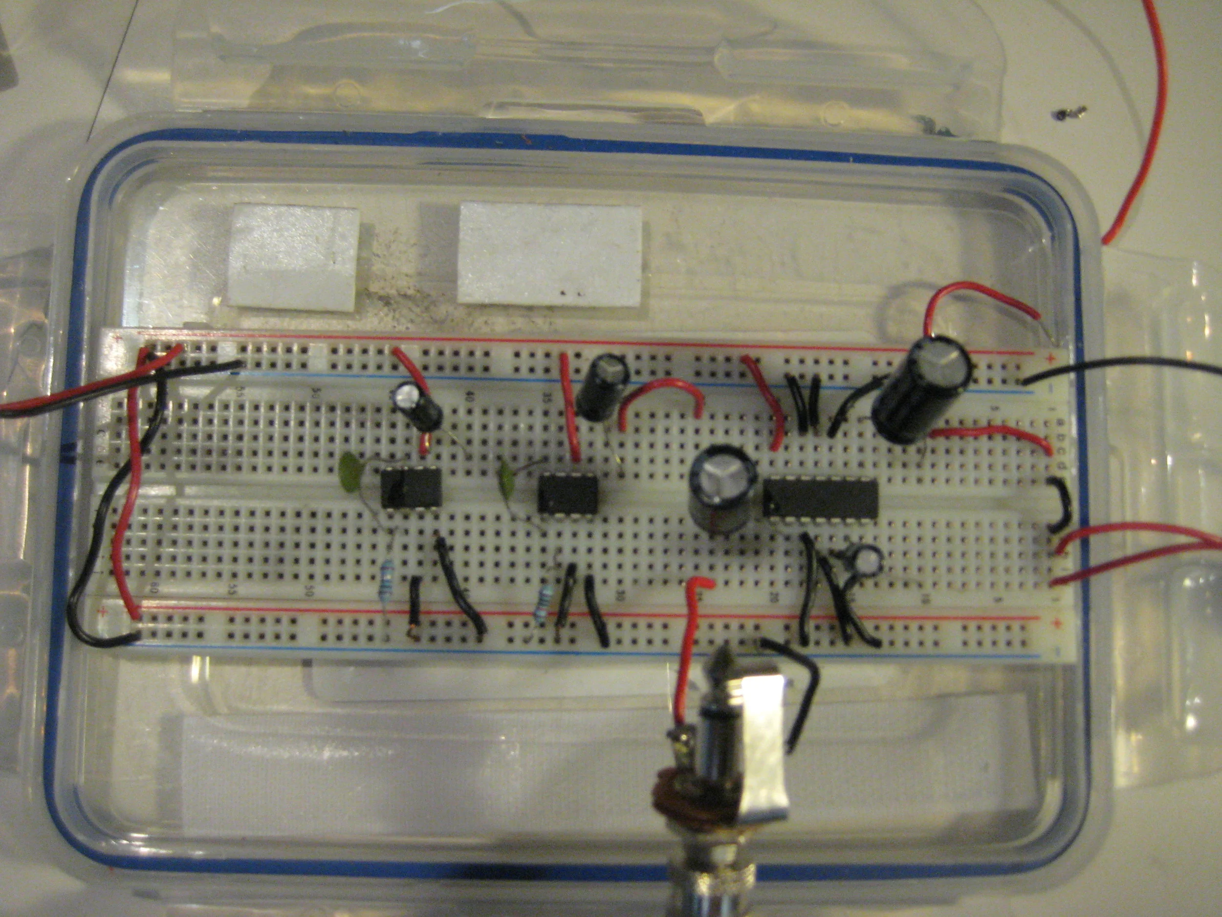 The initial prototype of The Rack also began on a breadboard utilizing one 5 watt LM 346 N and two LM 348 N amplifier chips. I used two 35v 1000μF capacitors in the input and output of the 5 watt chip, and 50v 10μF capacitors in the inputs of the first 2.5 watt chip which is then fed into the output of a second other 2.5 watt chip. Through this configuration, I discovered that routing the amplifier ships into one another creates a feedback loop of electronic noise. An additional feedback loop is created through the inclusion of a piezo microphone inputted to the 5 watt amplifier chip and placed in close proximity to a speaker connected to the output of the same amplifier chip. Click here to watch a video of the circuit being used in the empirical experimentation phase: https://www.youtube.com/watch?v=HV5D_flOK8w Once again, following the testing phase, I permanently soldered the capacitors and amplifier circuit into a more durable container, this time being a small wooden box that could contain the two circuits.