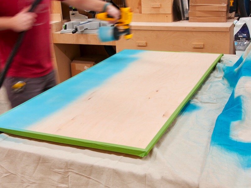 I sprayed on a few coats of TotalBoat Elixir in their Whaler Blue color using the Wagner Flexio again, and I taped off the outer edges of the back panel so I could still add some glue to those areas.