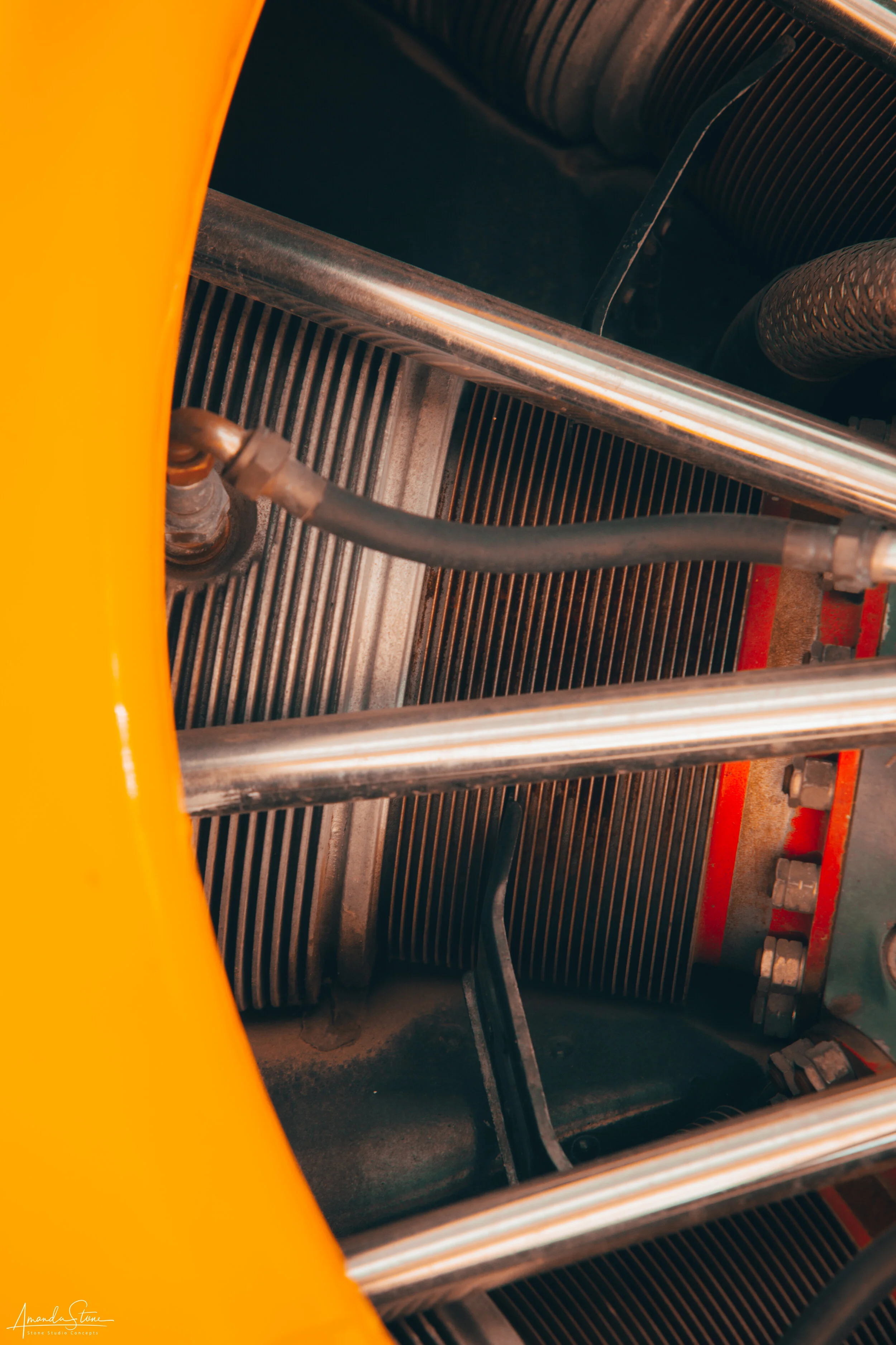 Close-up of a part of a machine with metal rods, tubing, and vents, partially covered by a yellow panel.