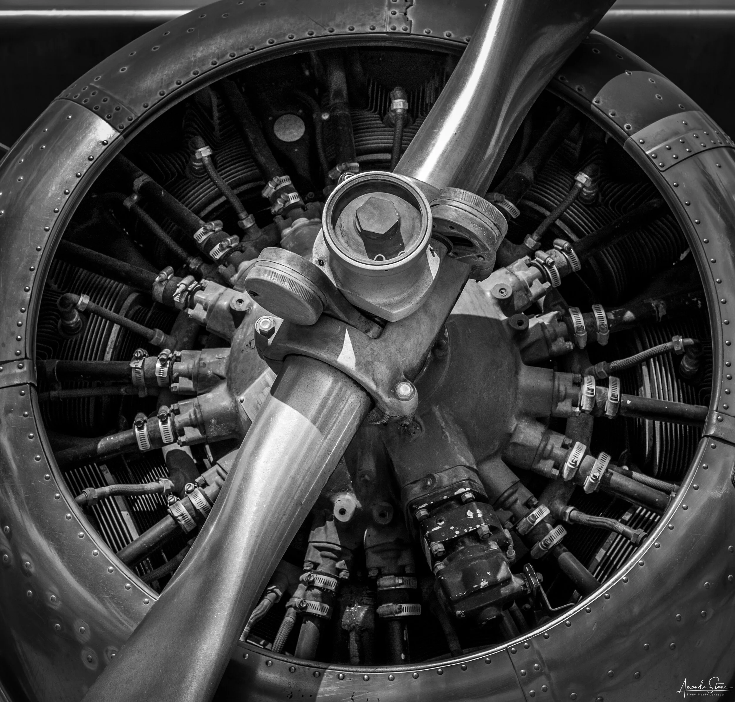 Close-up of an airplane engine with propeller blades, showcasing various mechanical components in black and white.