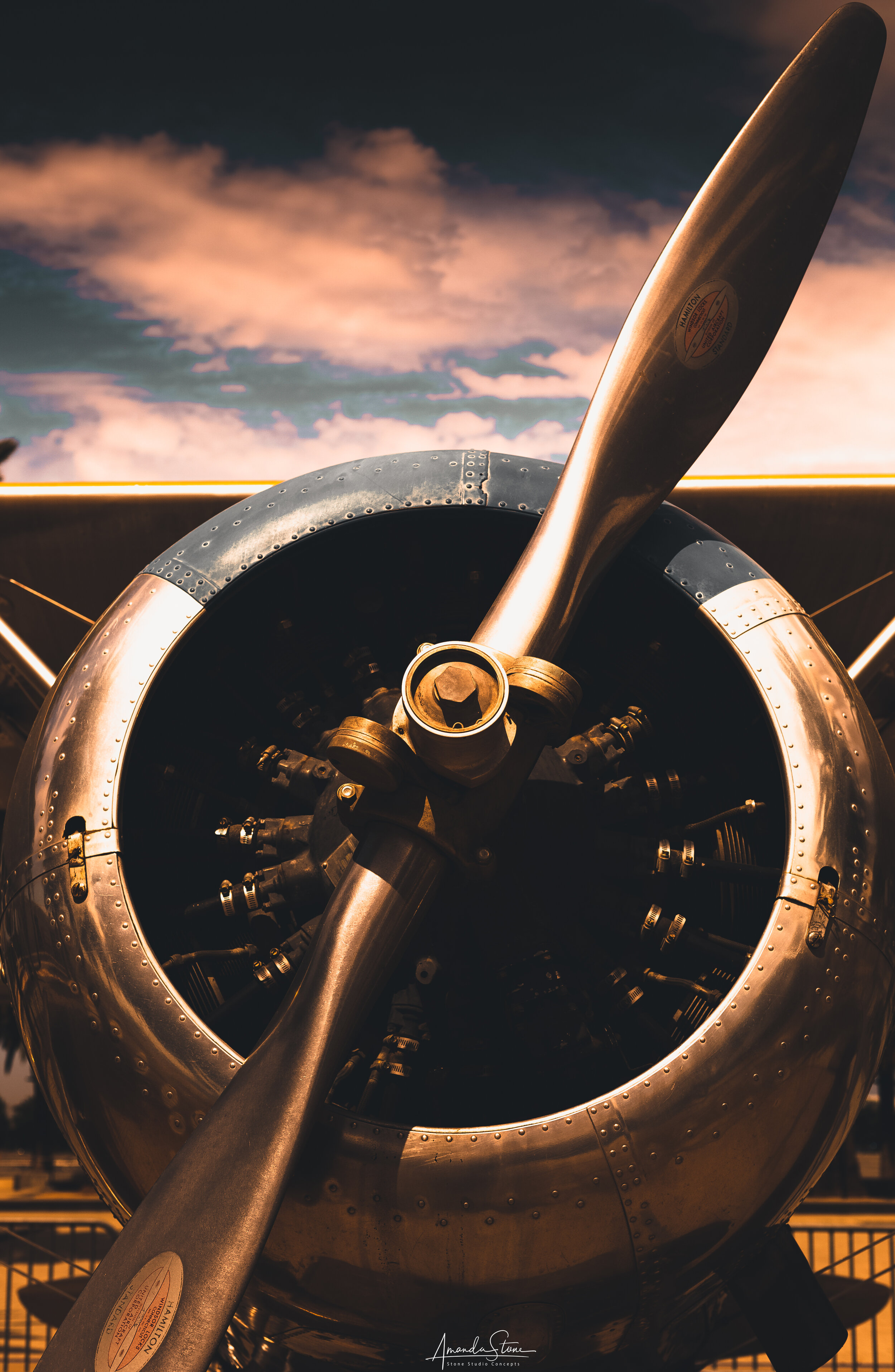 Close-up view of a vintage aircraft engine and propeller against a sky with pink clouds.