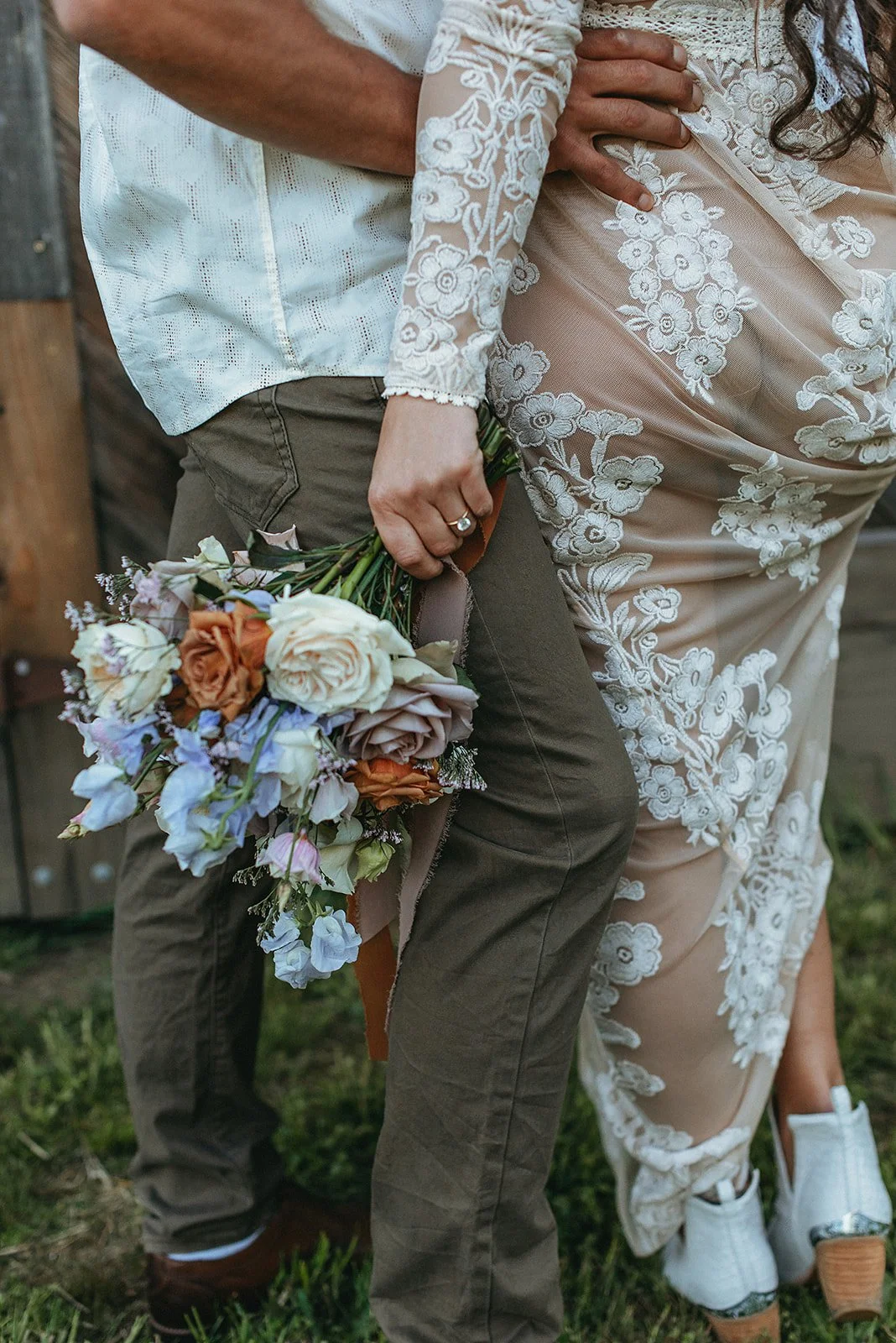 A person holding a colorful bouquet of flowers standing next to a person wearing a lace dress.
