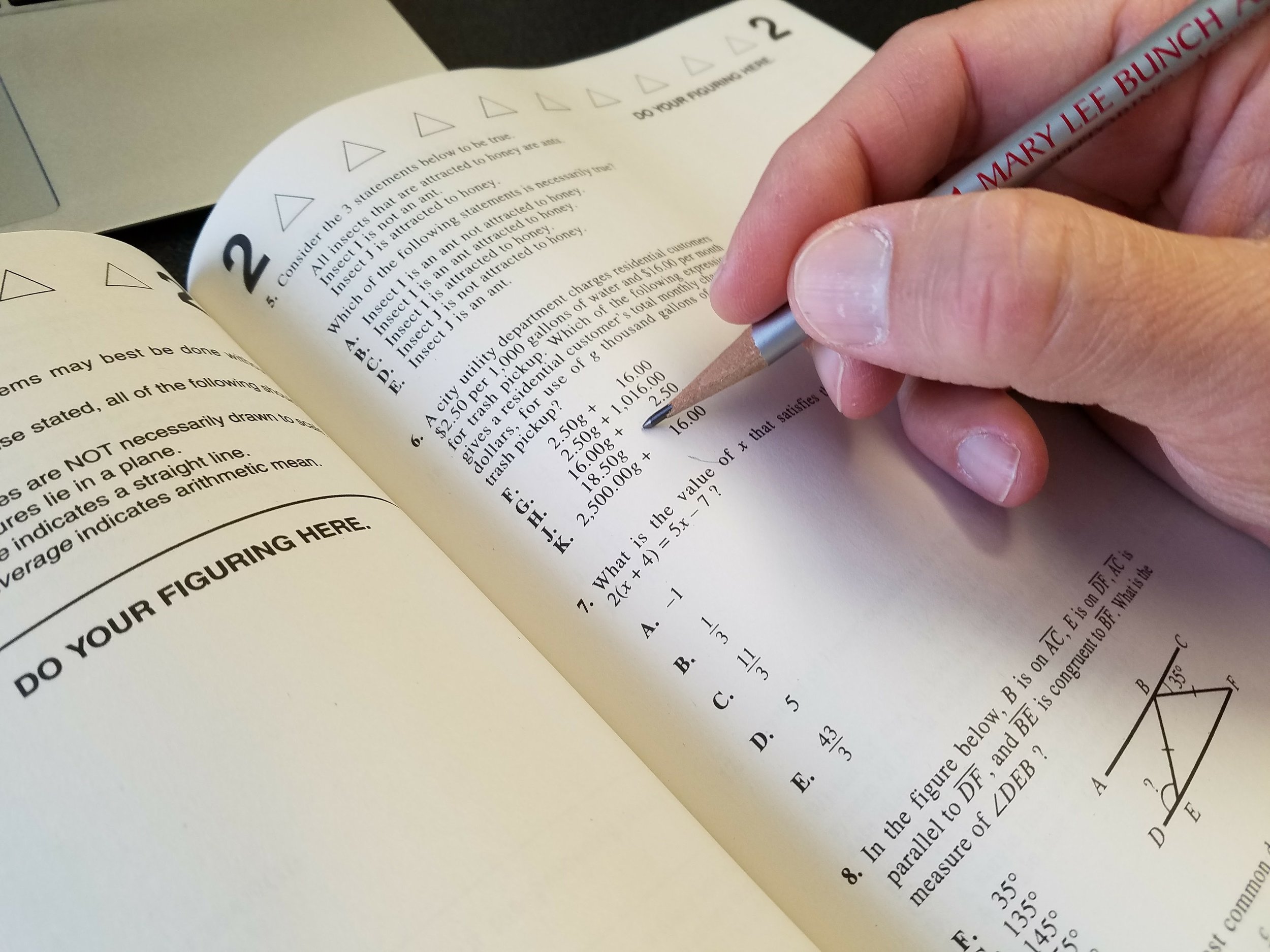 Person completing test questions in SAT prep book