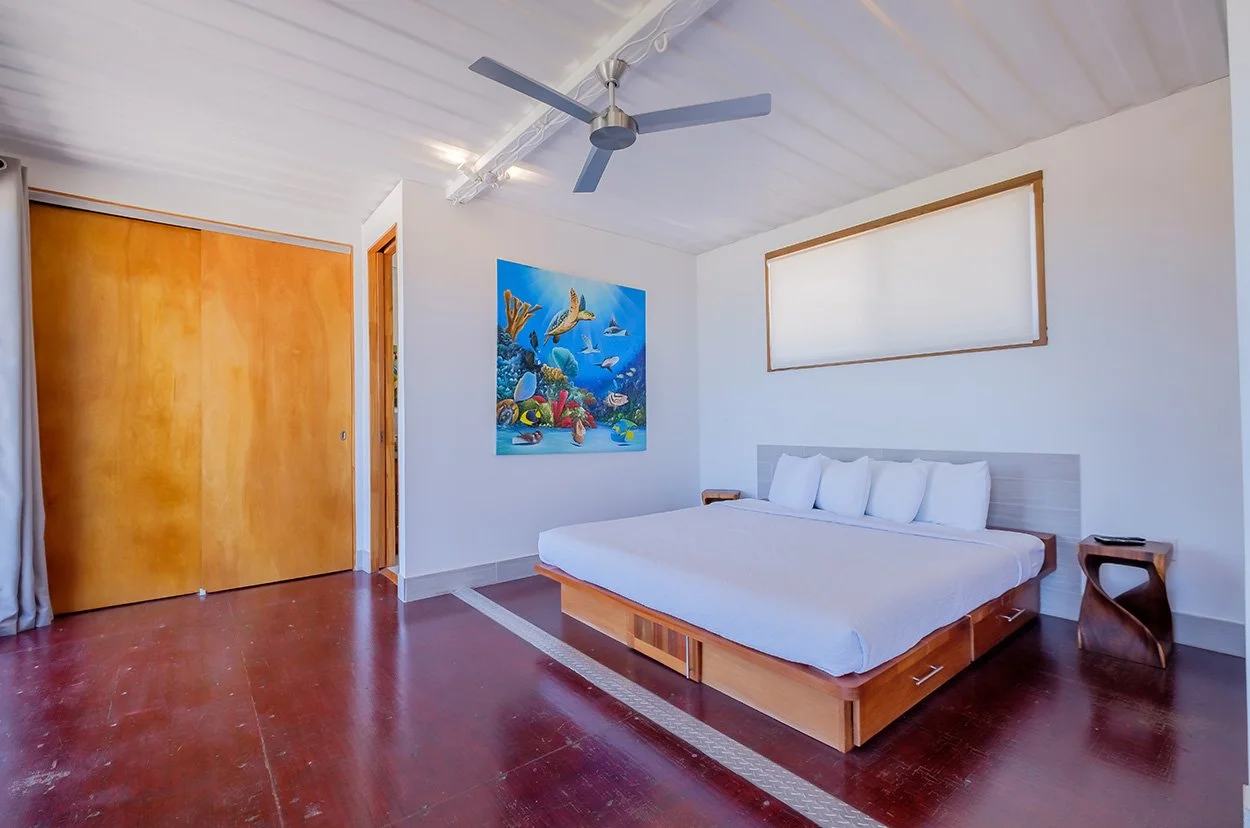 A king bed in the bedroom of Box House Boca Ciega, a vacation rental home on the ocean in San Pedro, Ambergris Caye, Belize.