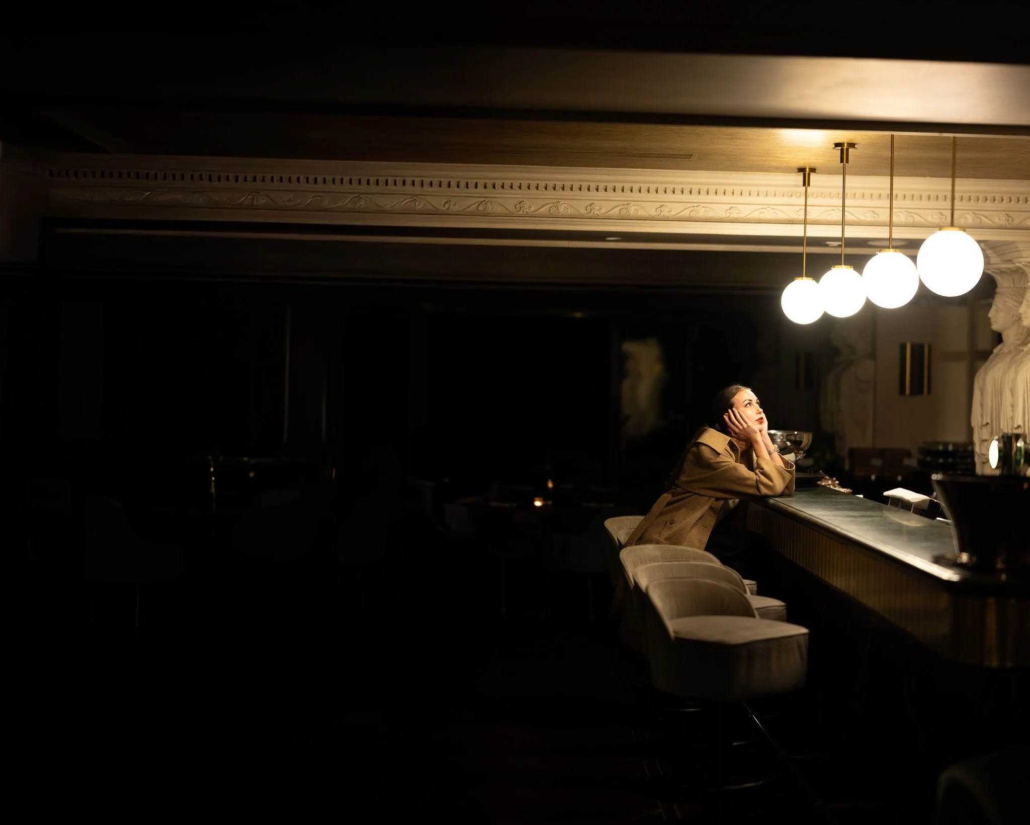 Woman alone at a dimly lit bar, photographed by Nicolas Rachline