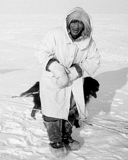 The late Wesley Ekak traveling on the tundra, wearing extremely warm caribou hide parka, boots, and mittens. 