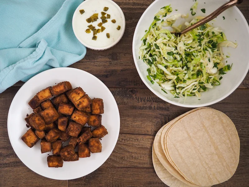 Crispy baked tofu tacos with cilantro lime slaw get a crispy, umami coating from a combination of nutritional yeast and soy sauce! Inspired by the best vegetarian tacos I’ve had on a trip to Sonoma! #vegan #vegetarian #taco #tofu #healthyrecipe