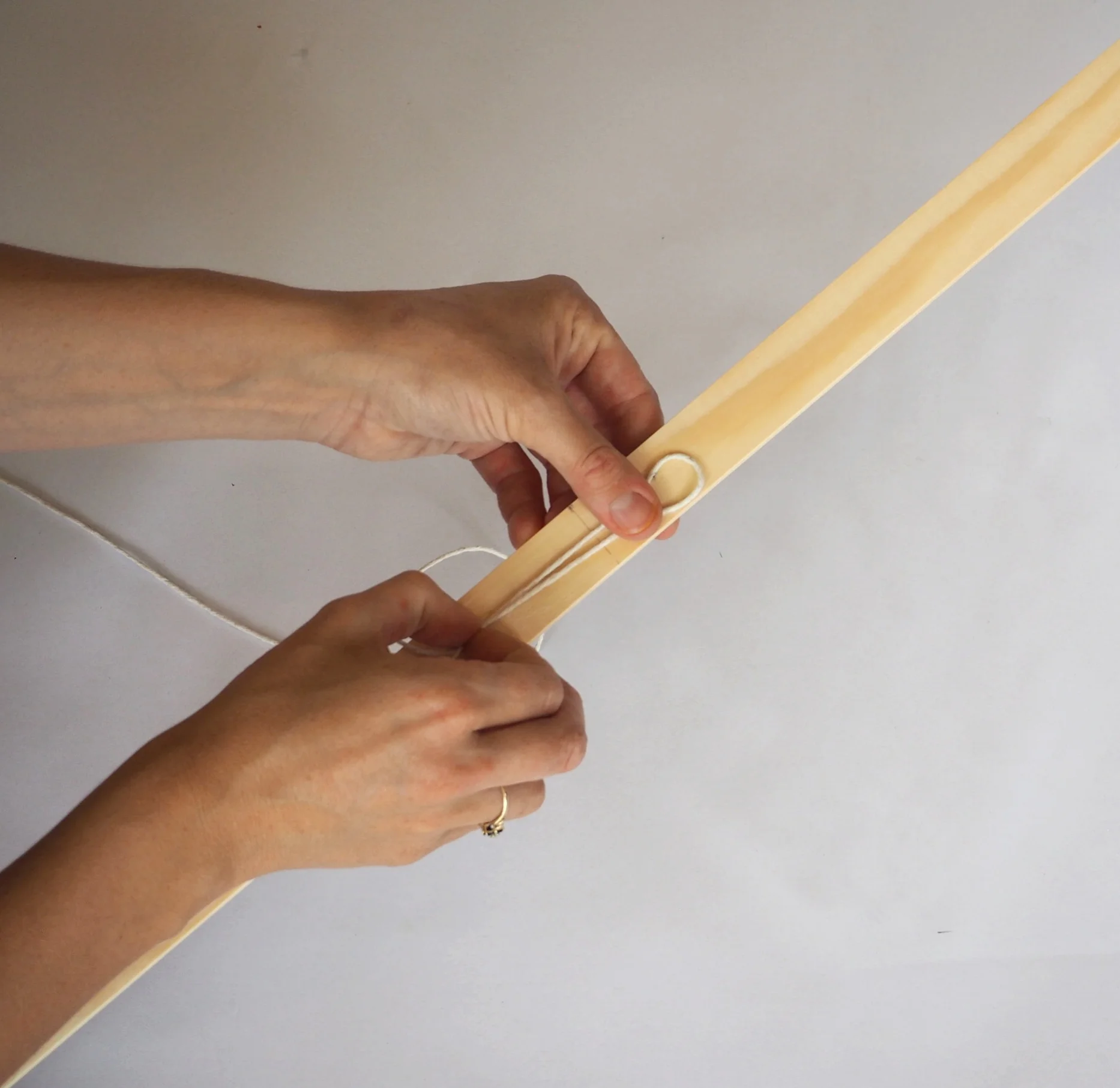  Take longest piece of string (150cm) and make a loop and hold flat on the centre line of the wood. 