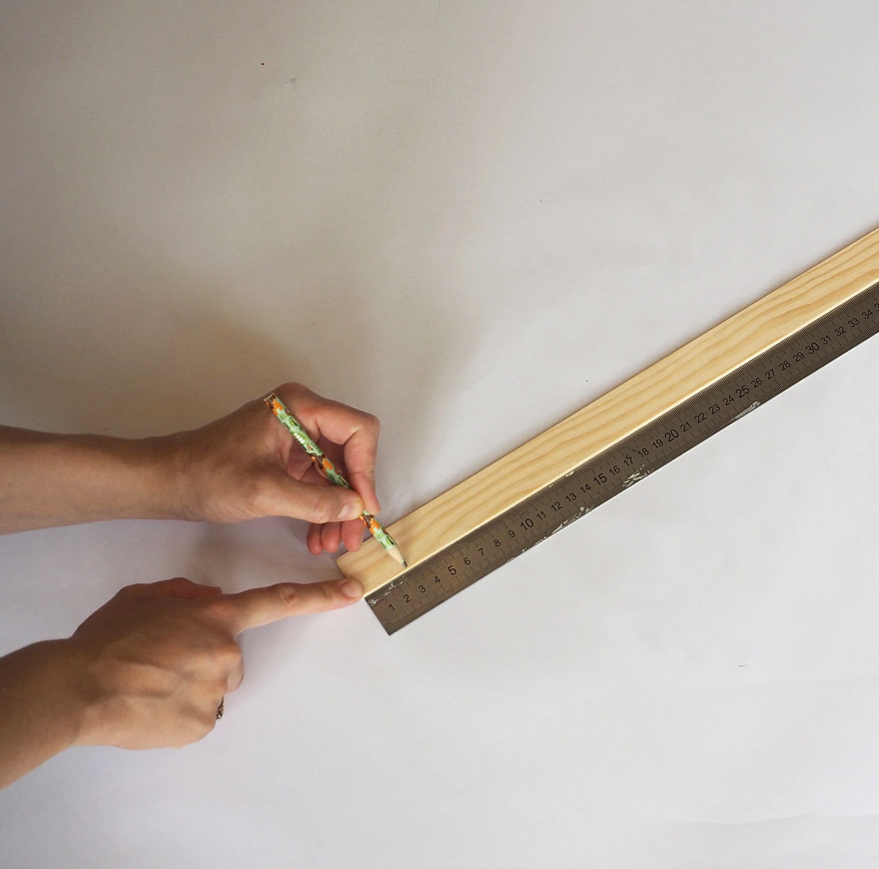  Take the long flexible piece of wood and draw a line three centimetres away from each end of the wood. 