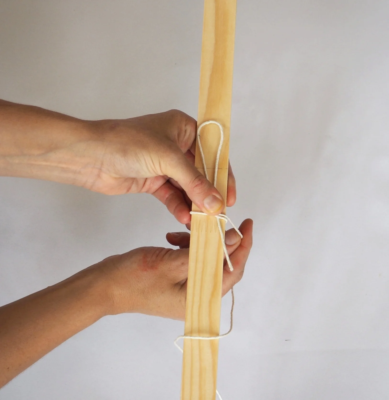  Continue to bind the string around the wood, making sure to pull it tight. 