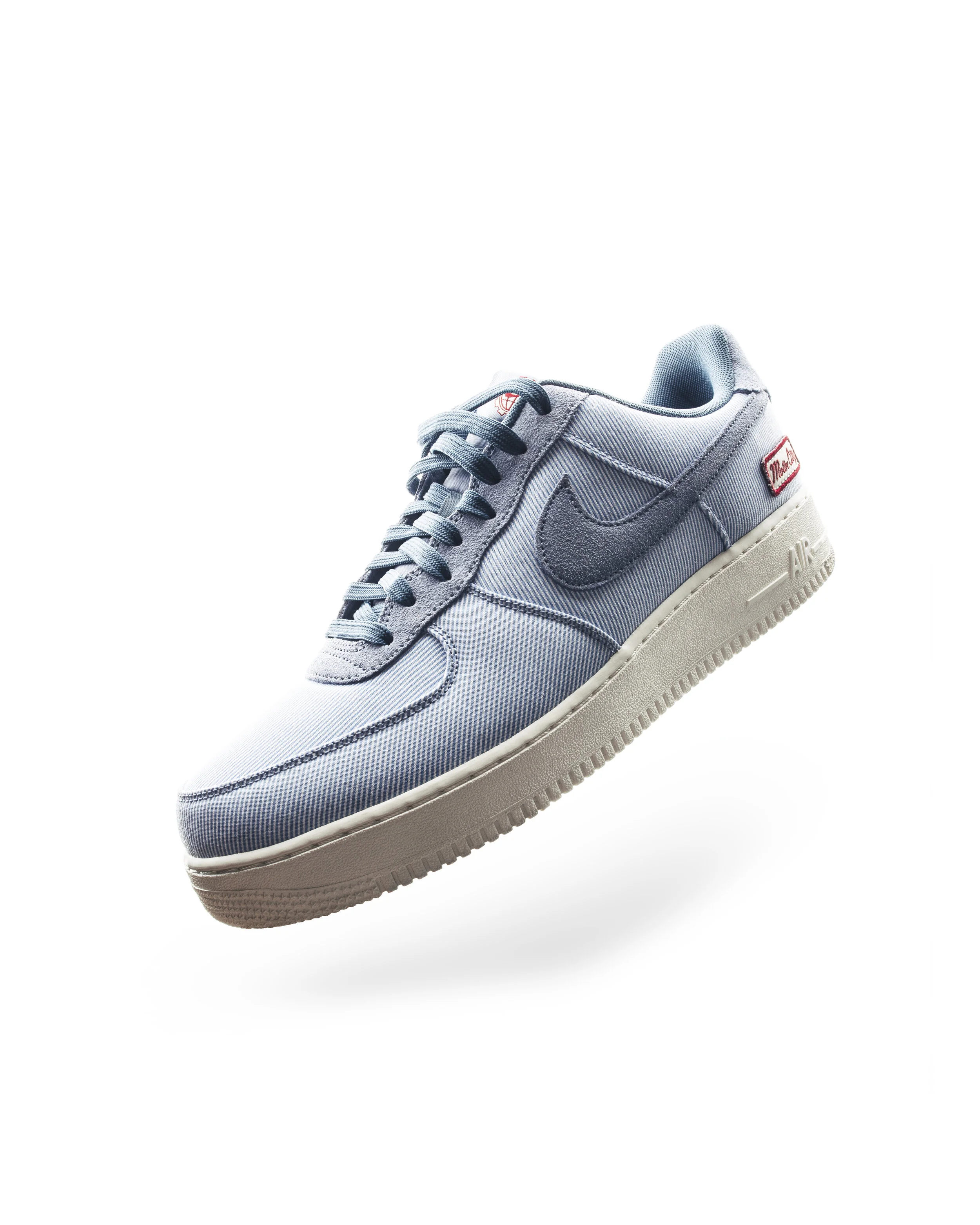 Light blue Nike Air Force 1 sneaker with gray accents, Lino logo, and red and white label on the heel.