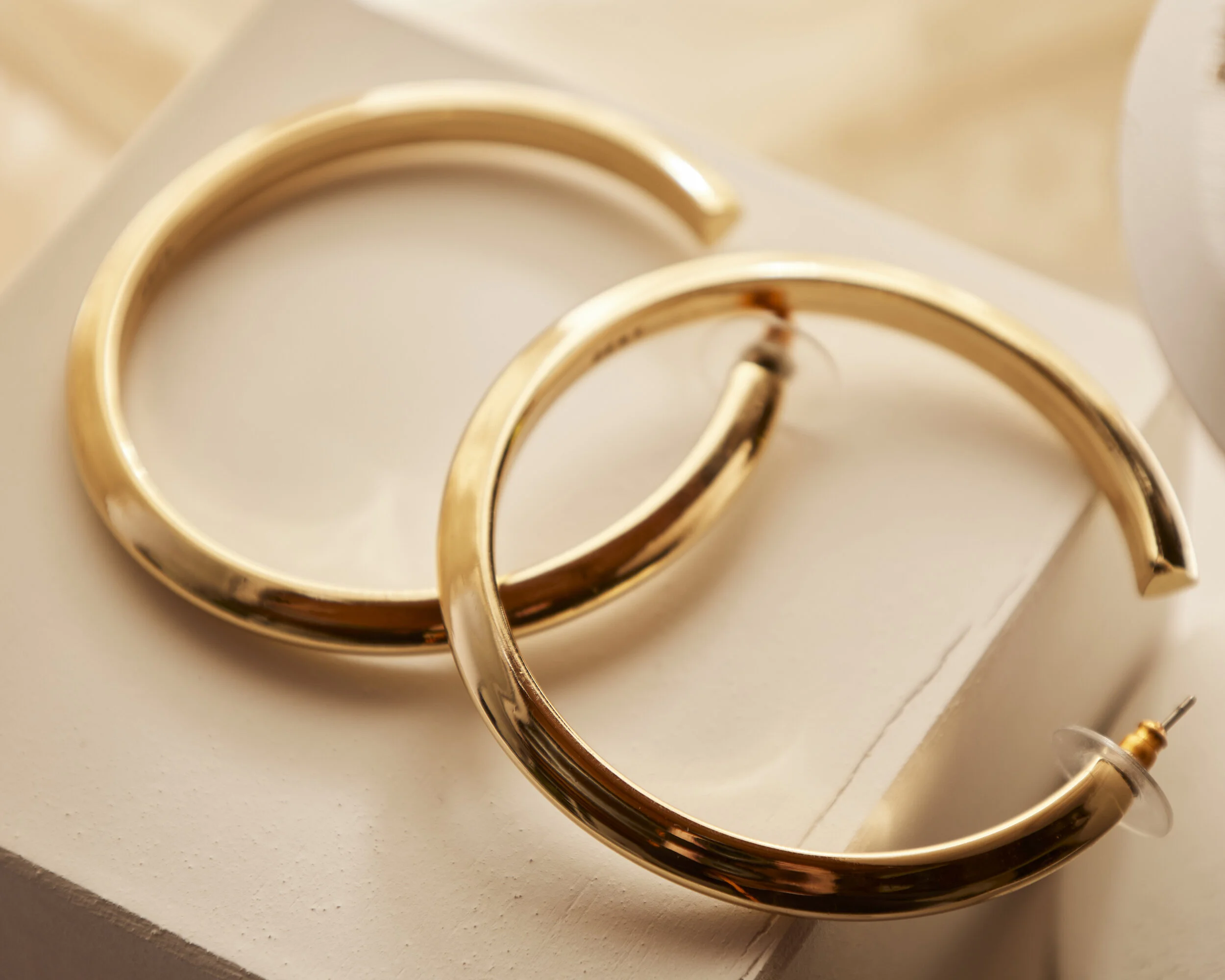 Gold hoop earrings resting on a white surface.