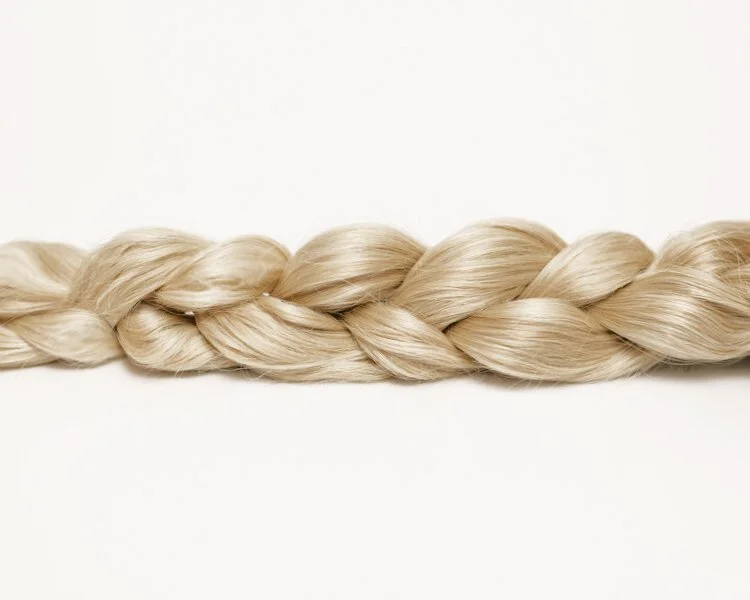 Close-up of a long, blonde braided hair strand on a plain white background.