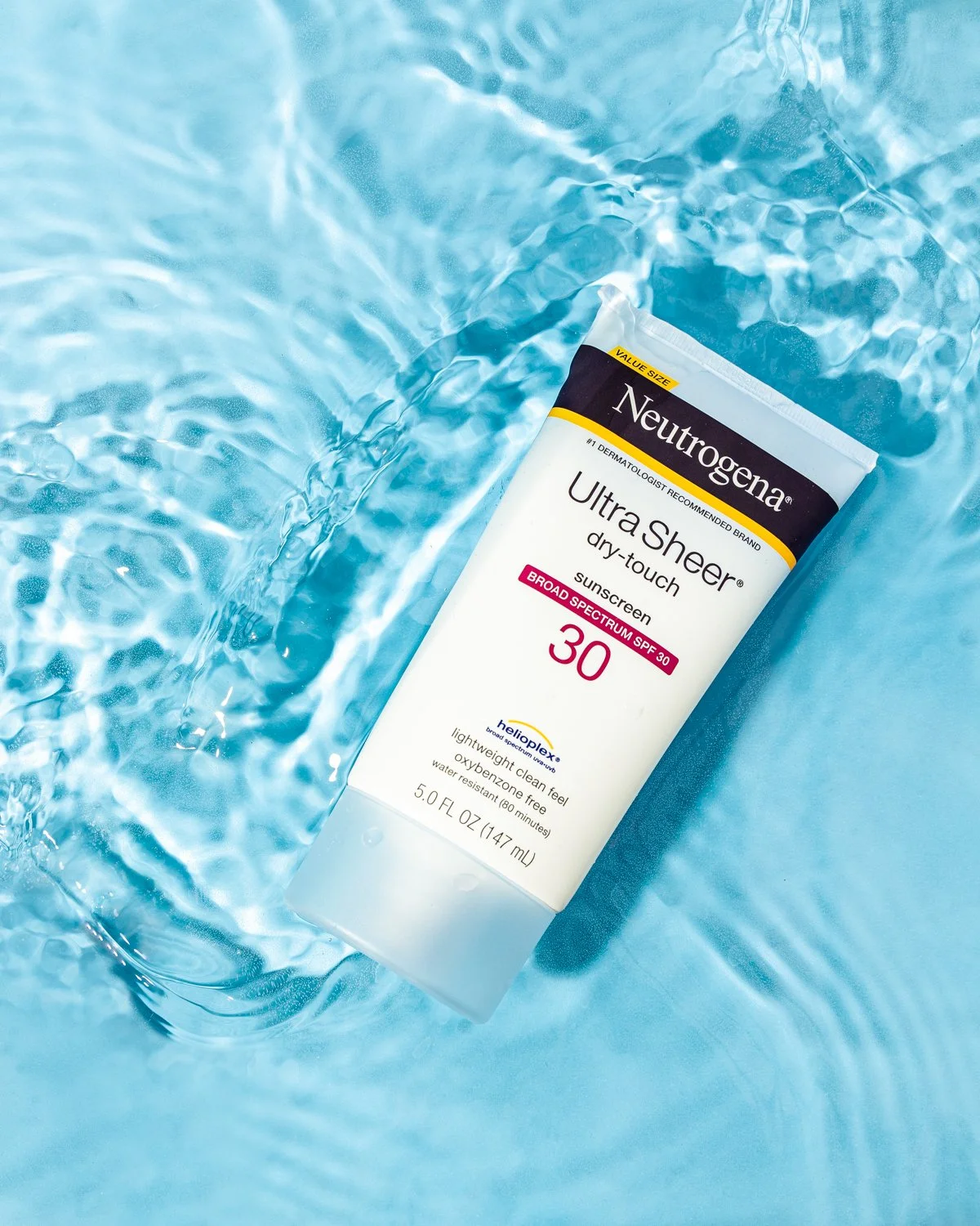 A tube of Neutrogena Ultra Sheer dry-touch sunscreen floating in a pool of water.