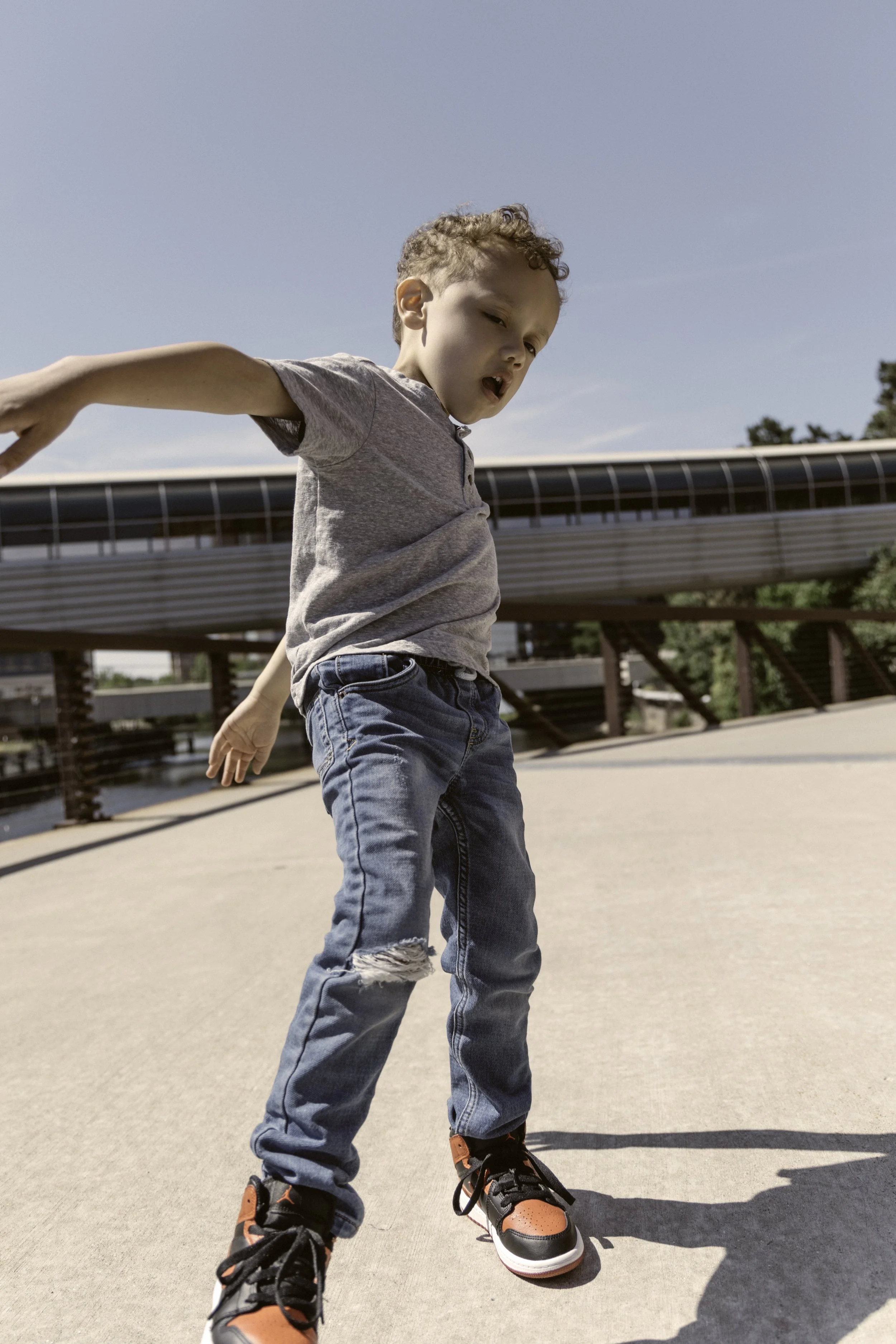 Young boy balancing on a skateboard on a sunny day at a park.