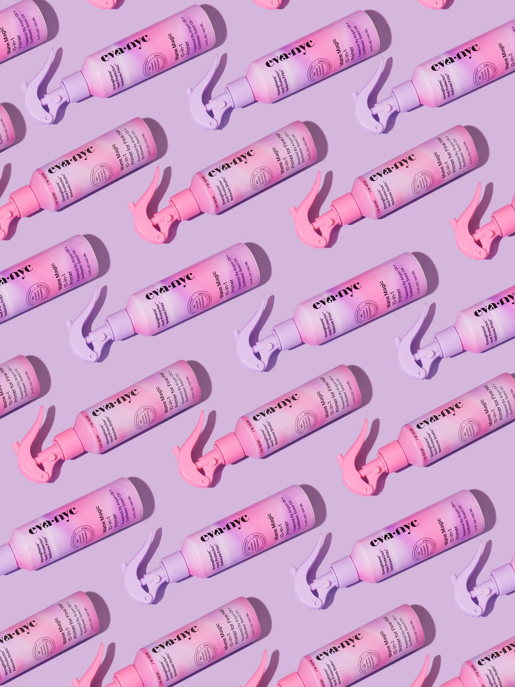 Multiple bottles of eva:nyc Blowout Mist arranged on a purple background, each with a pink spray nozzle facing downward and shadows cast to the right.