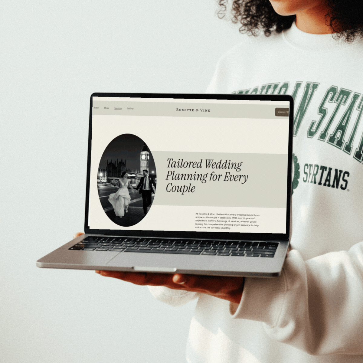 woman holding a laptop in her hand with a scrolling website on the screen