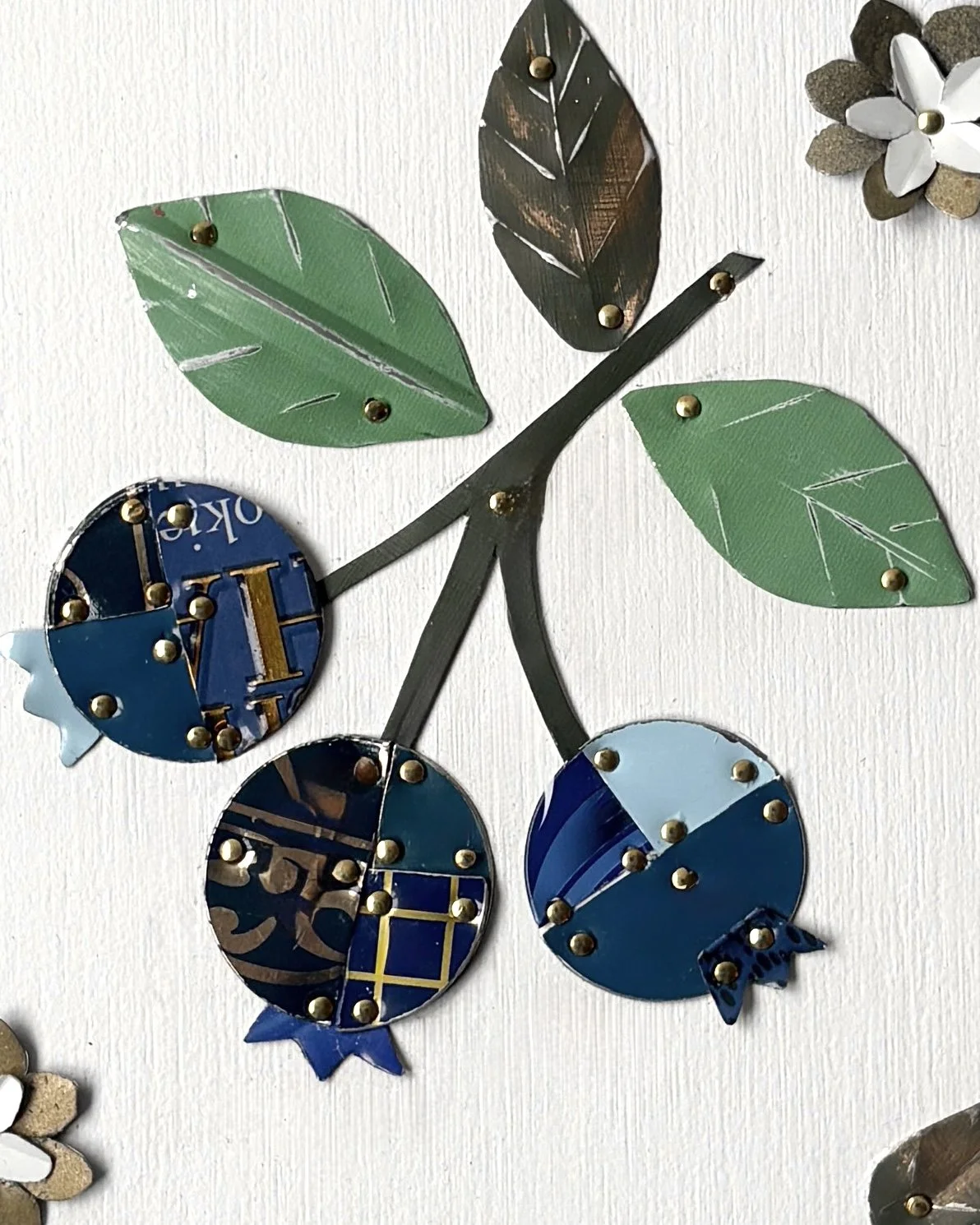 Close up of handmade blueberry tin collage showing reclaimed vintage tin textures and details