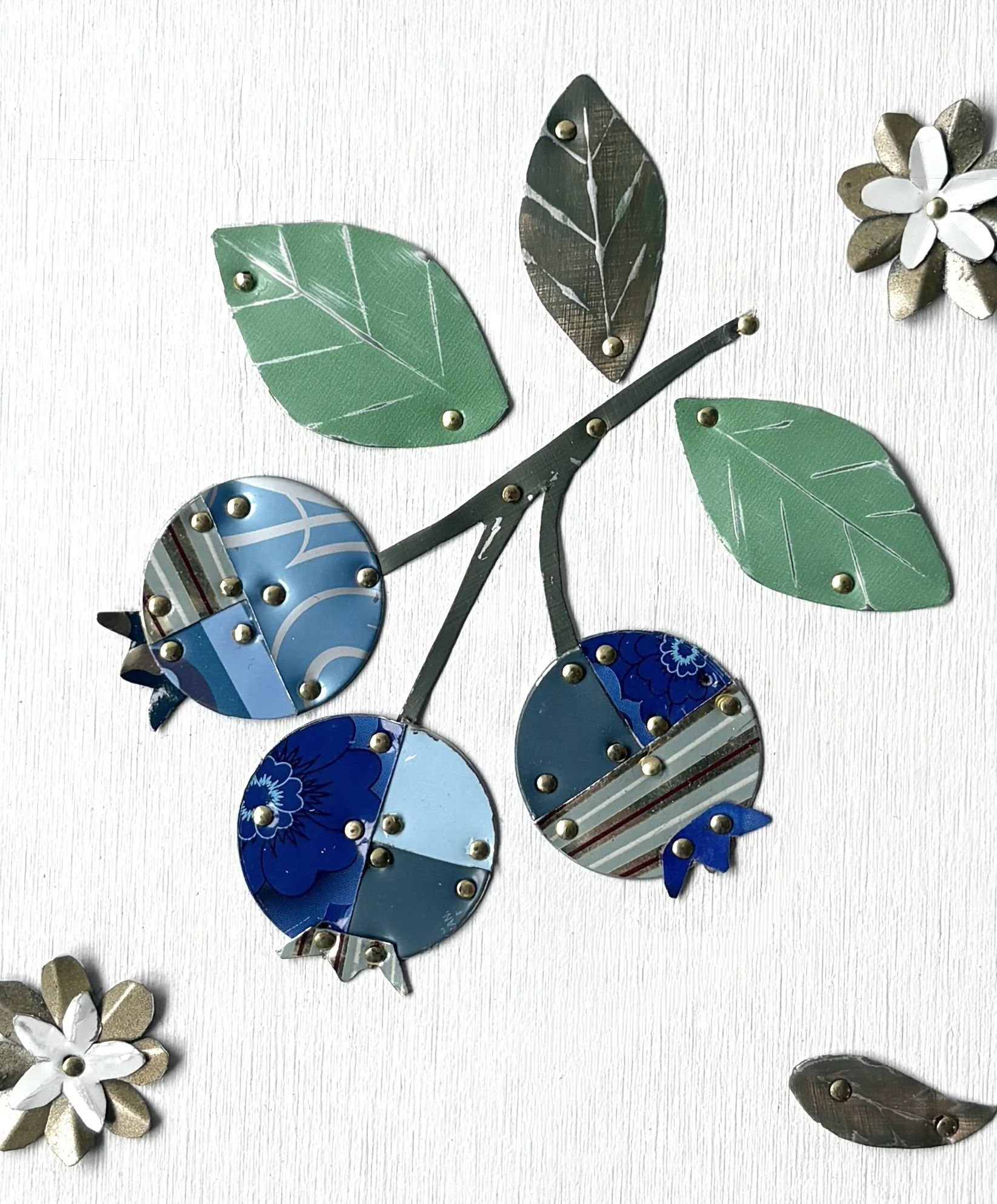 Close up of handmade blueberry tin collage showing reclaimed vintage tin textures and details