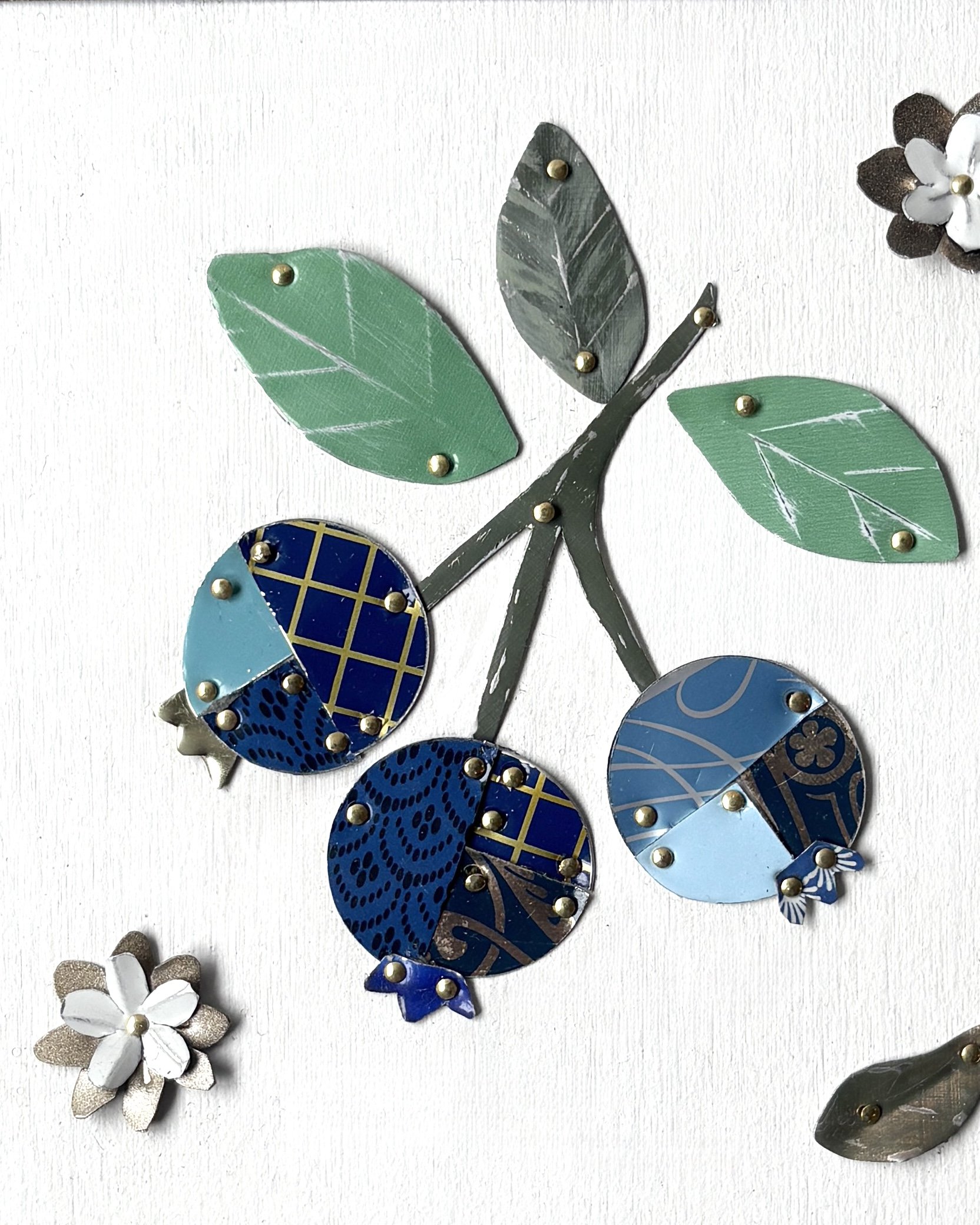 Close up of handmade blueberry tin collage showing reclaimed vintage tin textures and details