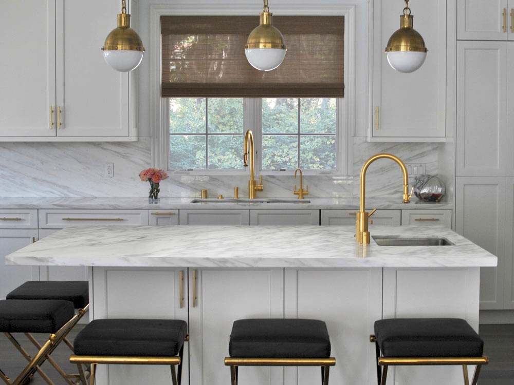 A Saghian-designed kitchen featuring satin brass finishes as well as his leather bar stools .