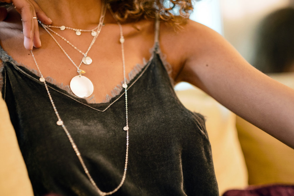 Model wears Talia Single Disc Necklace , Talia 5 Disc Necklace , Talia 10 Disc Necklace , and the Medallion Necklace .