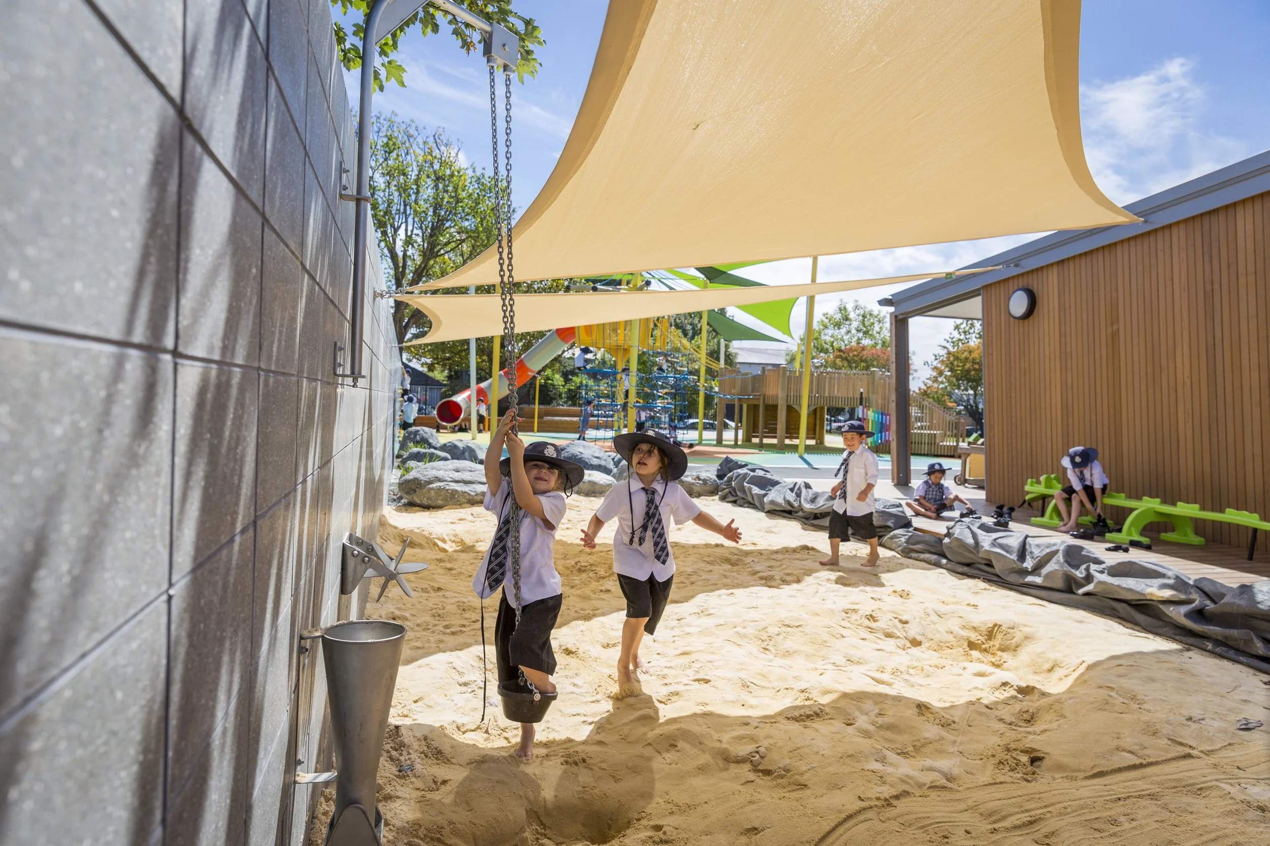 Shade sails which shelter the sandpit are supported by the concrete wall.