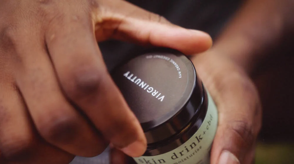 a pair of hands opening a jar of Virginutty CBD coconut oil